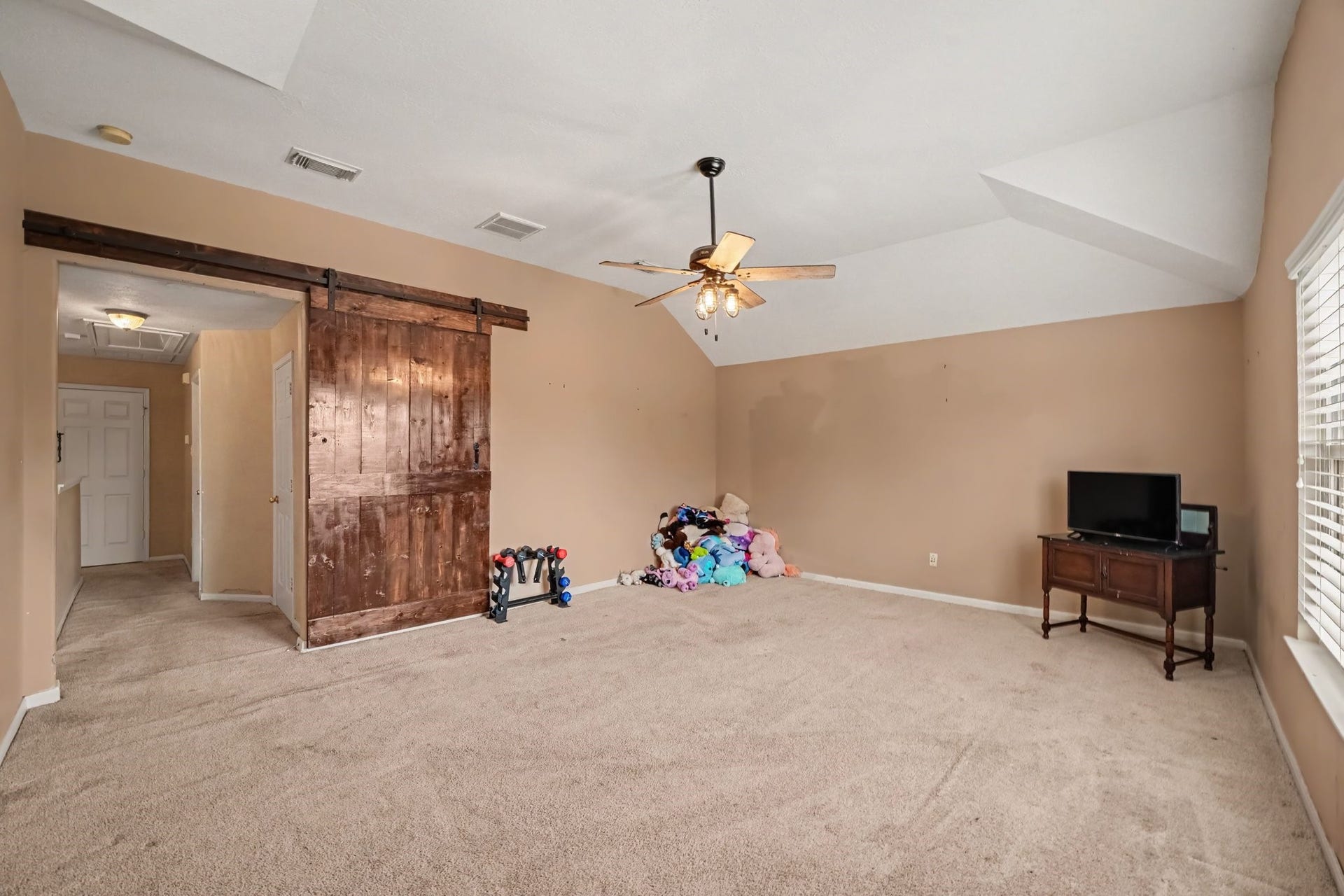 12807 Rocky Briar Lane, Tomball, TX 77377 The upstairs game room showcases its impressive size, vaulted ceiling, and custom barn door, with plenty of room for entertaining, gaming, or creating the ultimate hangout space.