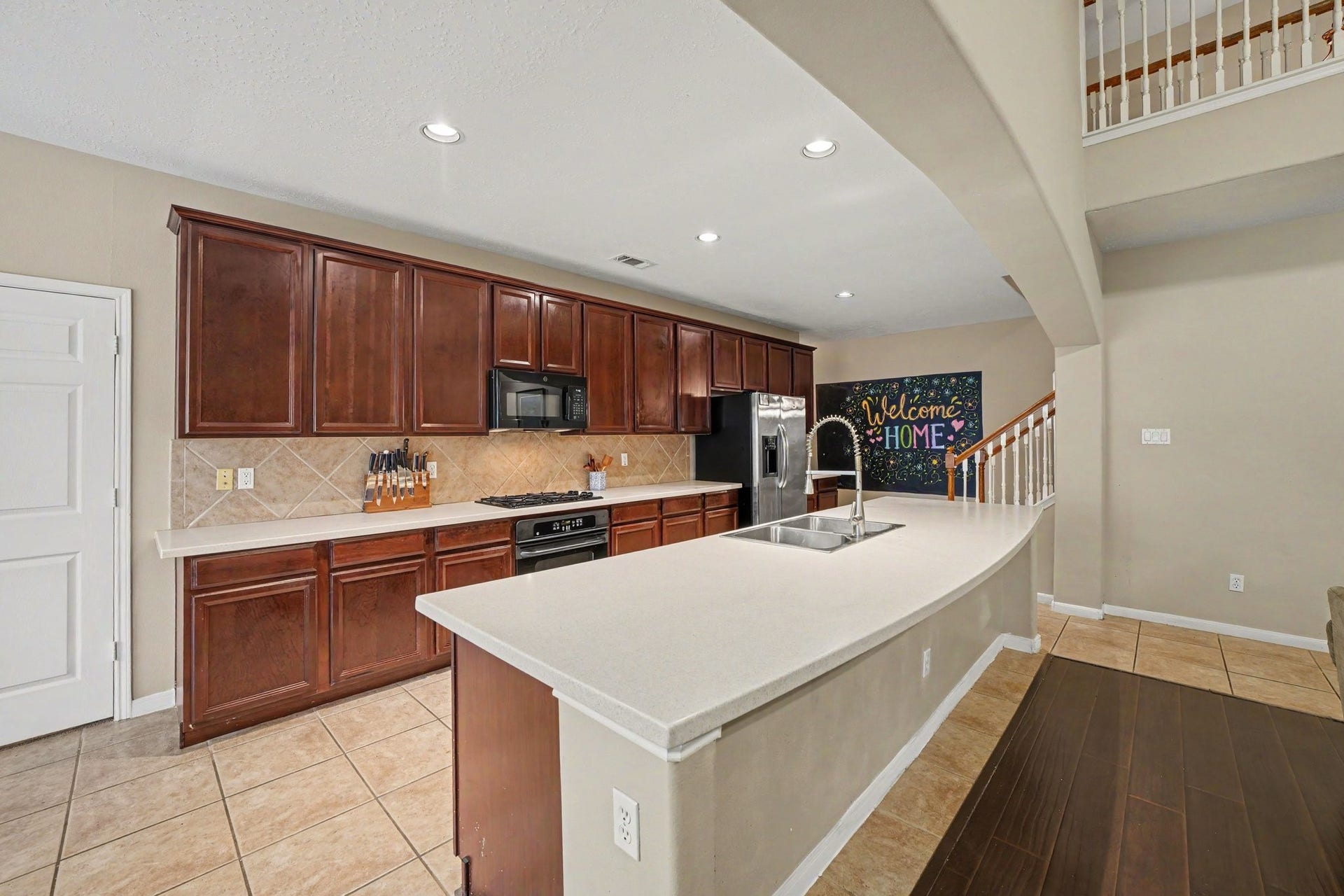 12807 Rocky Briar Lane, Tomball, TX 77377 A second view of the kitchen highlights the expansive breakfast bar with seating, rich wood cabinetry, and ample counter space. The open layout keeps the kitchen connected to the main living area, making it ideal for everyday living and entertaining.