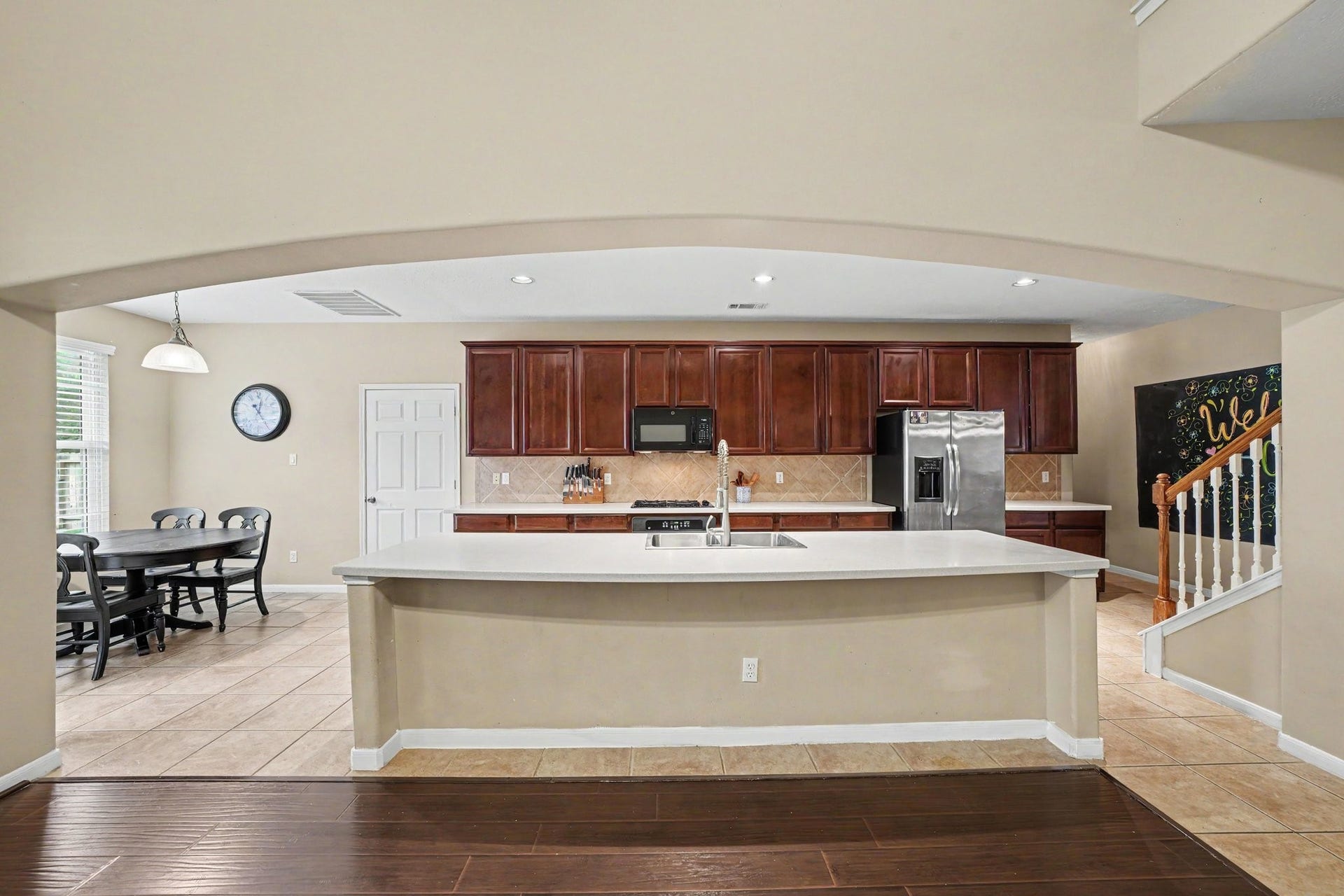 12807 Rocky Briar Lane, Tomball, TX 77377 A view from the living room showcases the open-concept kitchen with a large breakfast bar, warm wood cabinetry, and an easy flow between the kitchen and main living areas, perfect for everyday living and entertaining.