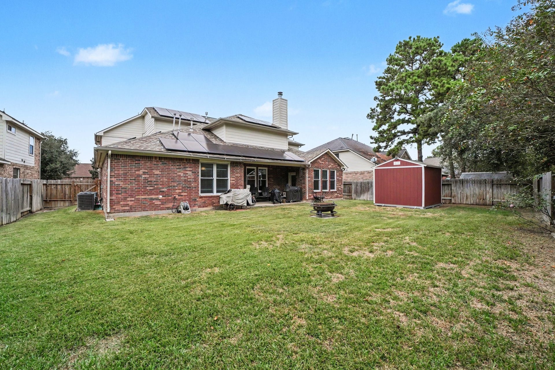 12807 Rocky Briar Lane, Tomball, TX 77377 AnThis backyard view showcases the covered patio, 1012 Tuff Shed, and solar panels seamlessly integrated into the roofline. With room to entertain, relax, and enjoy the outdoors, this backyard has plenty to offer!