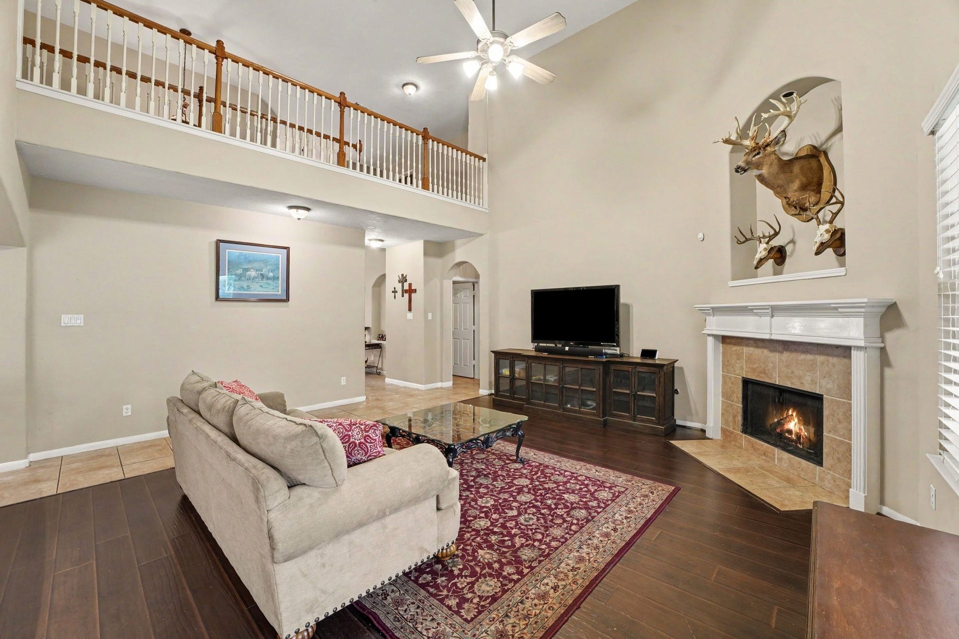 12807 Rocky Briar Lane, Tomball, TX 77377 A second view of the living room highlights the soaring ceilings, beautiful wood flooring, and fireplace, with an open view of the upstairs balcony that adds to the home's airy, inviting feel.