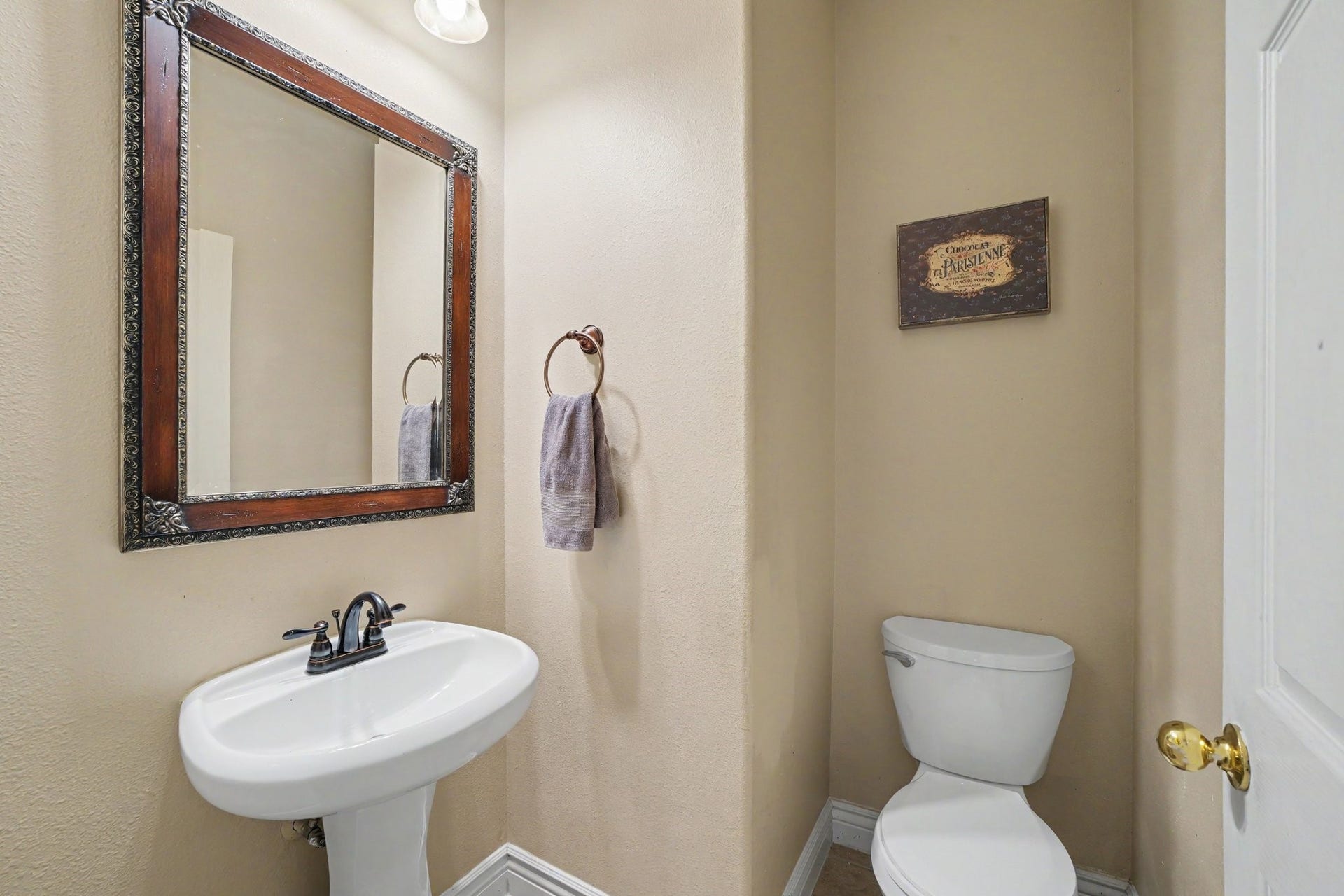 12807 Rocky Briar Lane, Tomball, TX 77377 Conveniently located downstairs, the half bath features a pedestal sink and decorative mirror, perfect for guests.