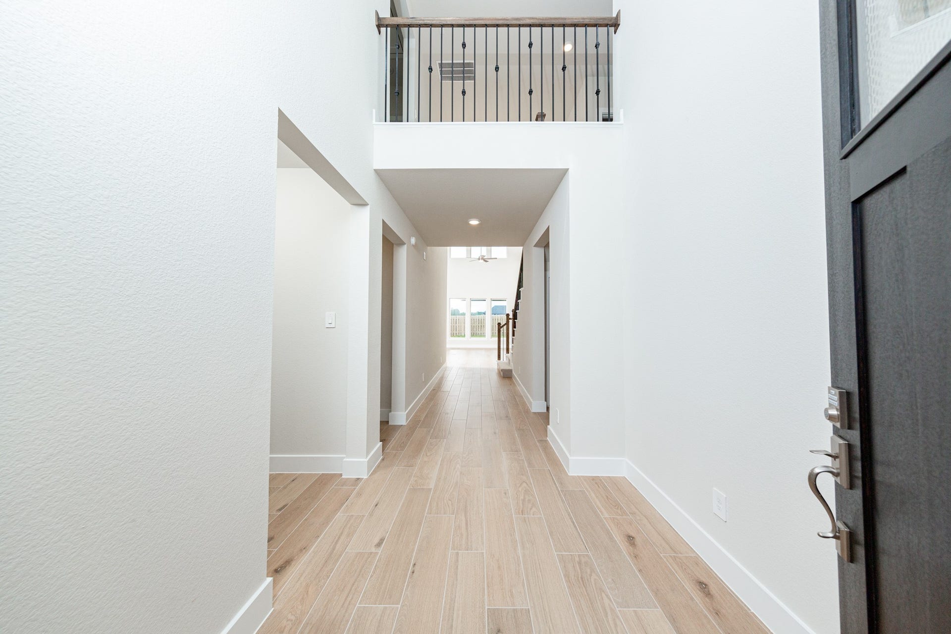 A bright and open interior entryway focuses on modern design and natural light. The space is amplified by high ceilings, recessed lighting, gorgeous tile plank flooring - creating an airy and welcoming first impression.