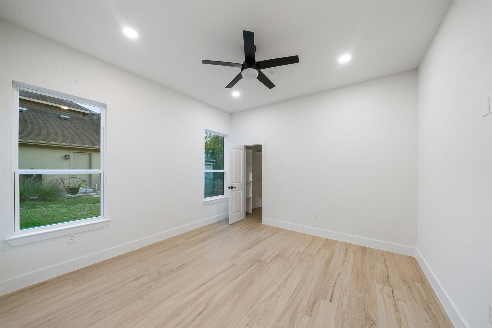 4833 W Fork Boulevard, Conroe, TX 77304 Spacious bedroom featuring beautiful wood-look flooring, a modern ceiling fan, recessed lighting, and large windows. Neutral finishes and an adjoining closet provide comfort and versatility.
