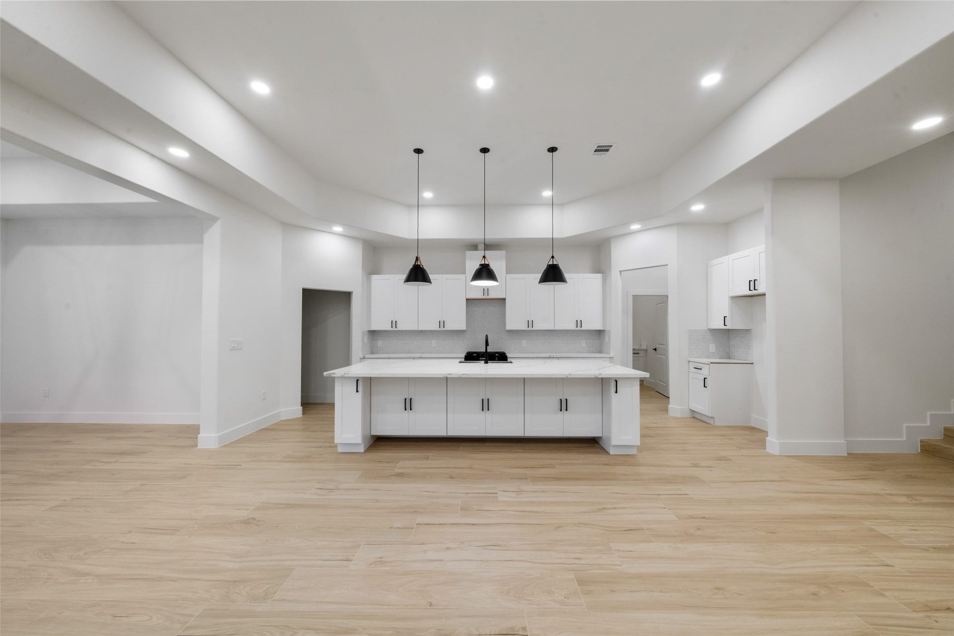 4833 W Fork Boulevard, Conroe, TX 77304 Beautifully designed kitchen serves as the centerpiece of the home, showcasing an oversized island, custom cabinetry, and sophisticated pendant lighting. The open layout creates a seamless connection to the spacious living and dining areas.
