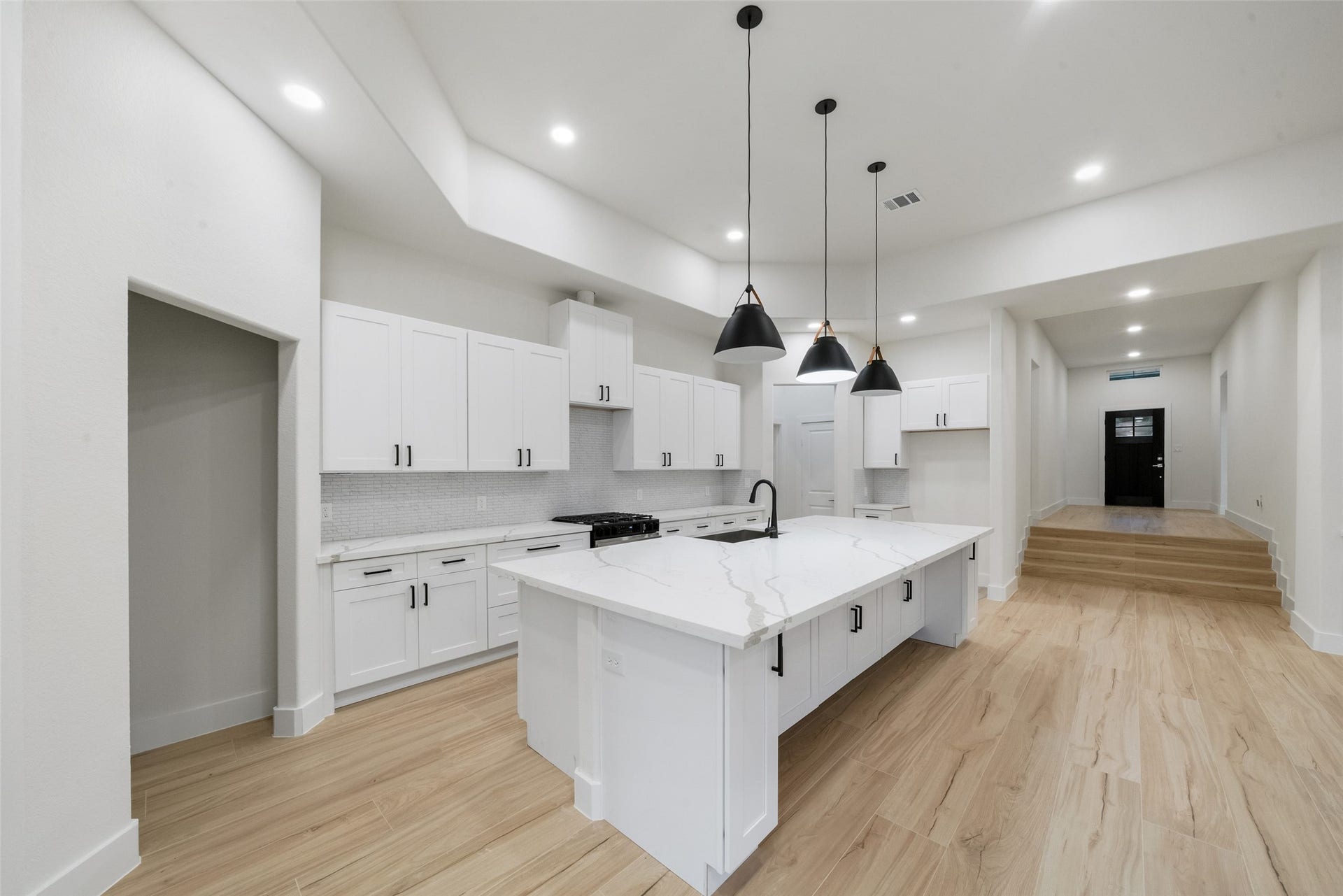 4833 W Fork Boulevard, Conroe, TX 77304 Stunning custom kitchen featuring an oversized island with beautiful marble-look countertops, elegant white cabinetry, sleek black hardware, and designer pendant lighting. A spacious layout and abundant cabinetry create the perfect combination of style and functionality.