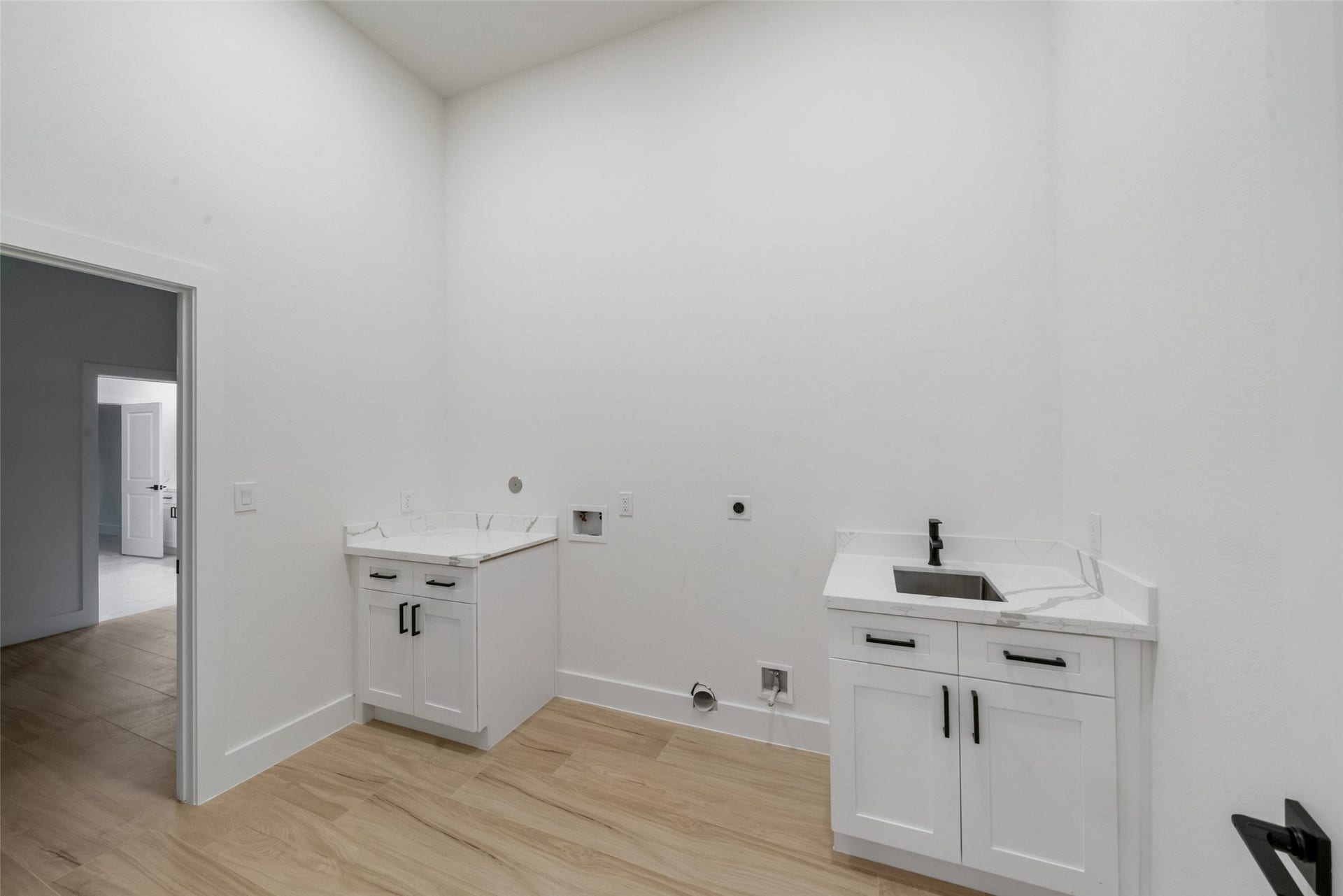 4833 W Fork Boulevard, Conroe, TX 77304 Generously sized laundry room featuring custom white cabinetry, marble-look countertops, a stainless steel utility sink, and sleek black fixtures. Thoughtfully designed with ample workspace, storage, and room for laundry appliances to make everyday tasks effortless.