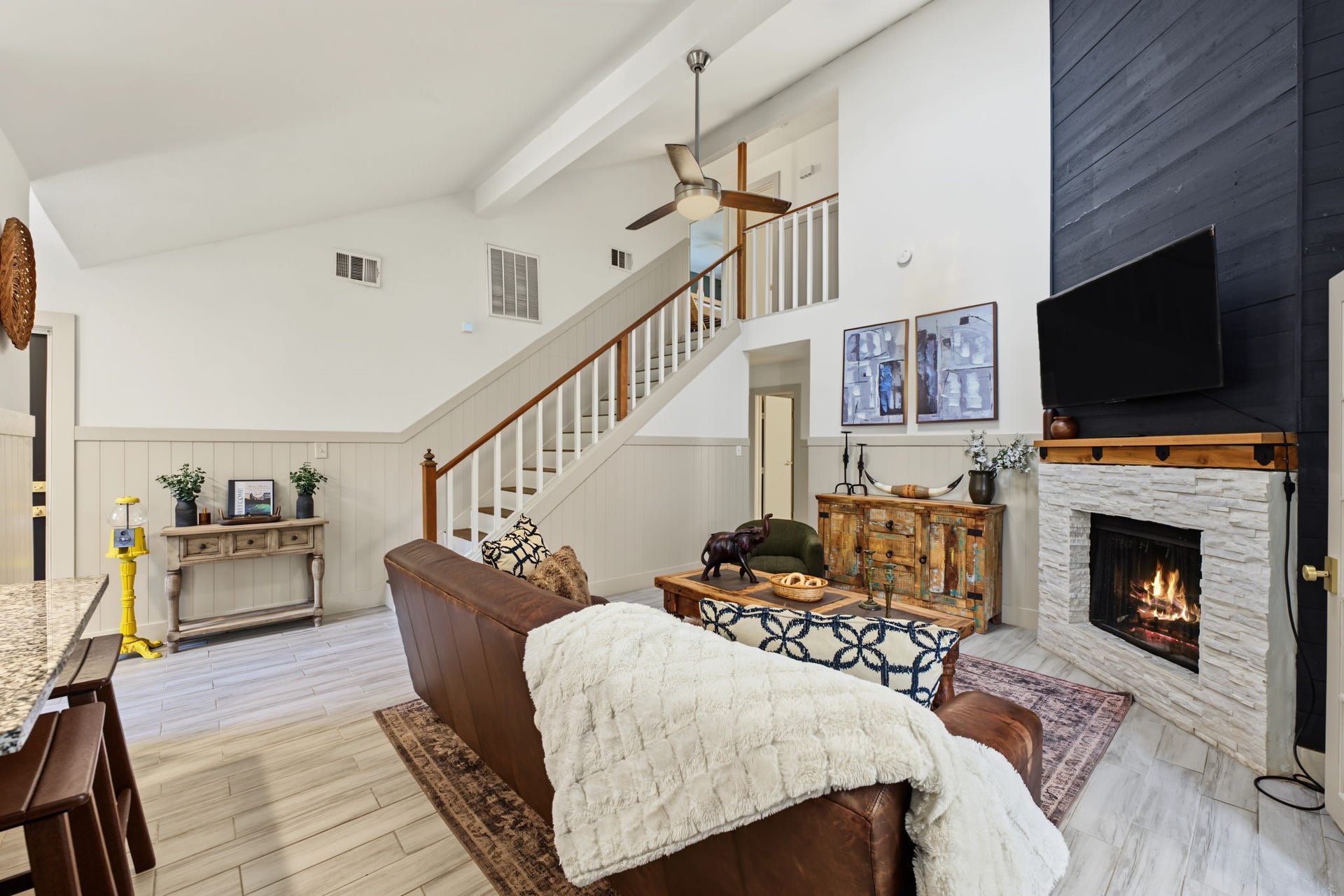 5006 Deer Point Drive, Spring, TX 77389 Soaring vaulted living room boasts a wood beam, floor-to-ceiling black shiplap and a white stacked stone fireplace with rustic wood mantel!