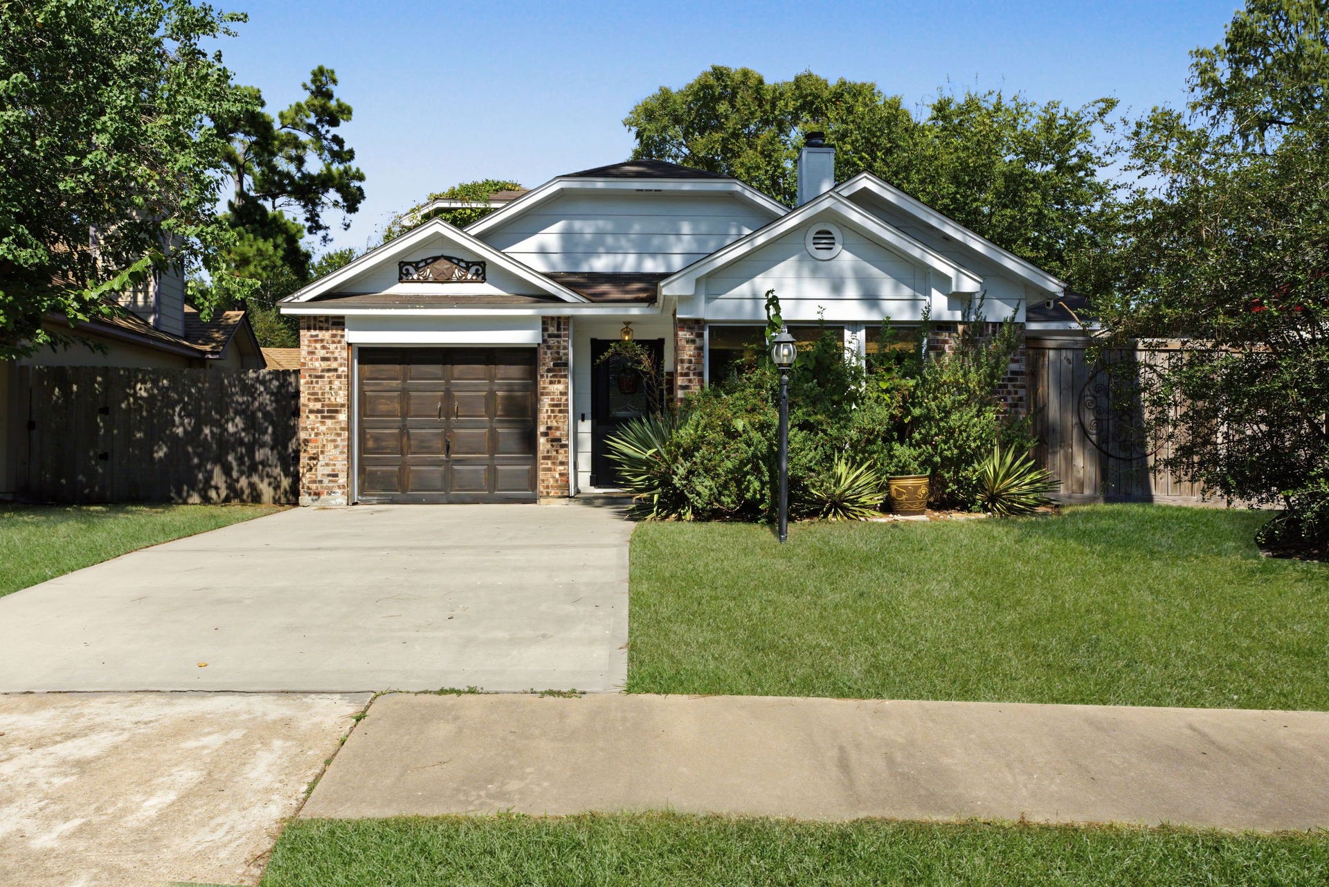 5006 Deer Point Drive, Spring, TX 77389 Charming brick and white siding exterior framed by mature trees, a lamp post and lush landscaping!