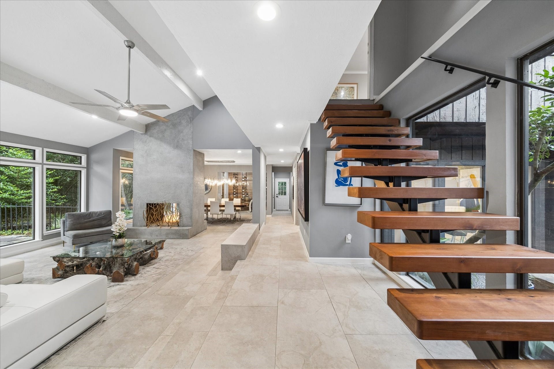 2411 Oakbank Drive, Kingwood, TX 77339 As you enter, you will find a spacious open living area with large windows, a sleek wood and metal floating staircase, and a contemporary fireplace. The neutral palette and abundant natural light create a welcoming and stylish atmosphere.
