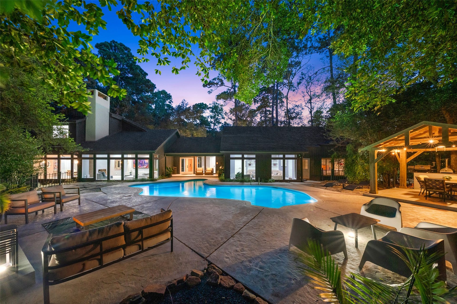 2411 Oakbank Drive, Kingwood, TX 77339 A spacious backyard featuring a sleek swimming pool, surrounded by ample patio space and lush greenery, ideal for outdoor relaxation and entertainment.