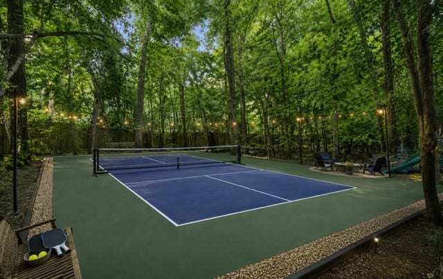 2411 Oakbank Drive, Kingwood, TX 77339 Experience ultimate outdoor leisure with this virtually staged pickleball court nestled amid lush greenery, perfect for both relaxation and recreation.