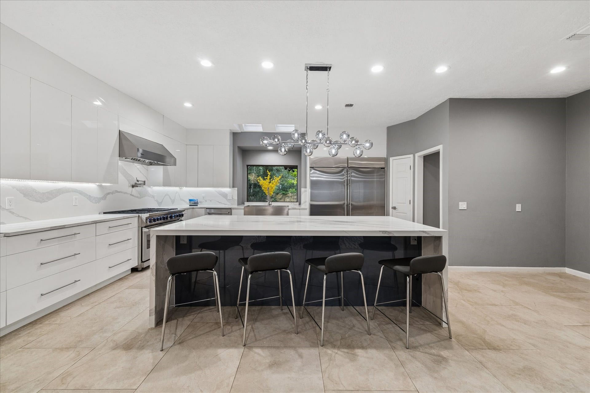 2411 Oakbank Drive, Kingwood, TX 77339 Spacious modern kitchen with sleek white cabinetry, a large island with seating, stainless steel appliances, and contemporary lighting. Ideal for cooking and entertaining.