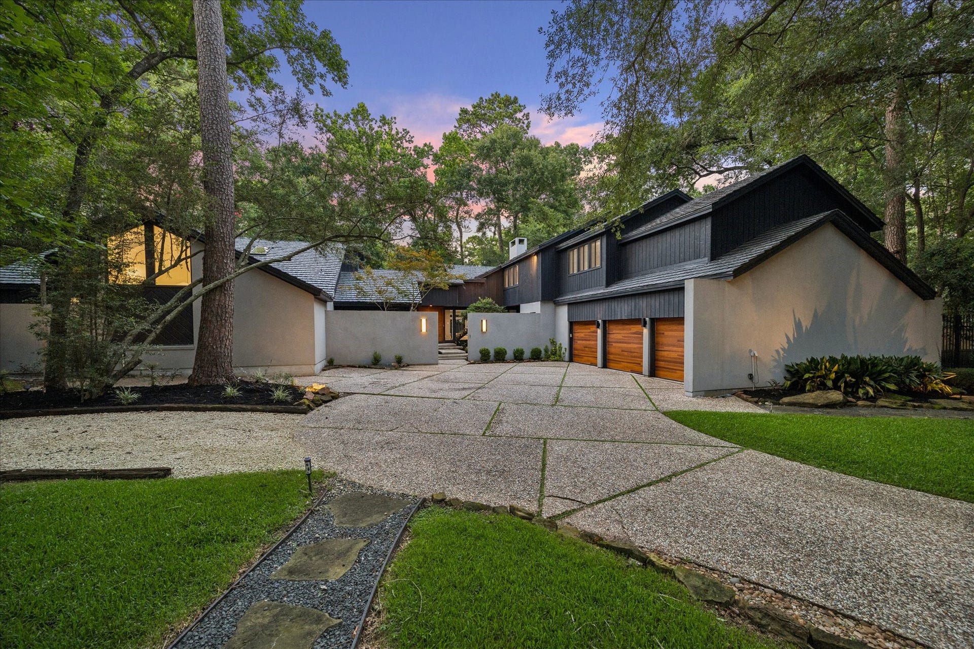 2411 Oakbank Drive, Kingwood, TX 77339 Welcome to 2411 Oakbank. This home features a sleek exterior with a multi-car garage, nestled in a lush, wooded setting. Its expansive driveway and contemporary architecture create a welcoming, stylish entrance.