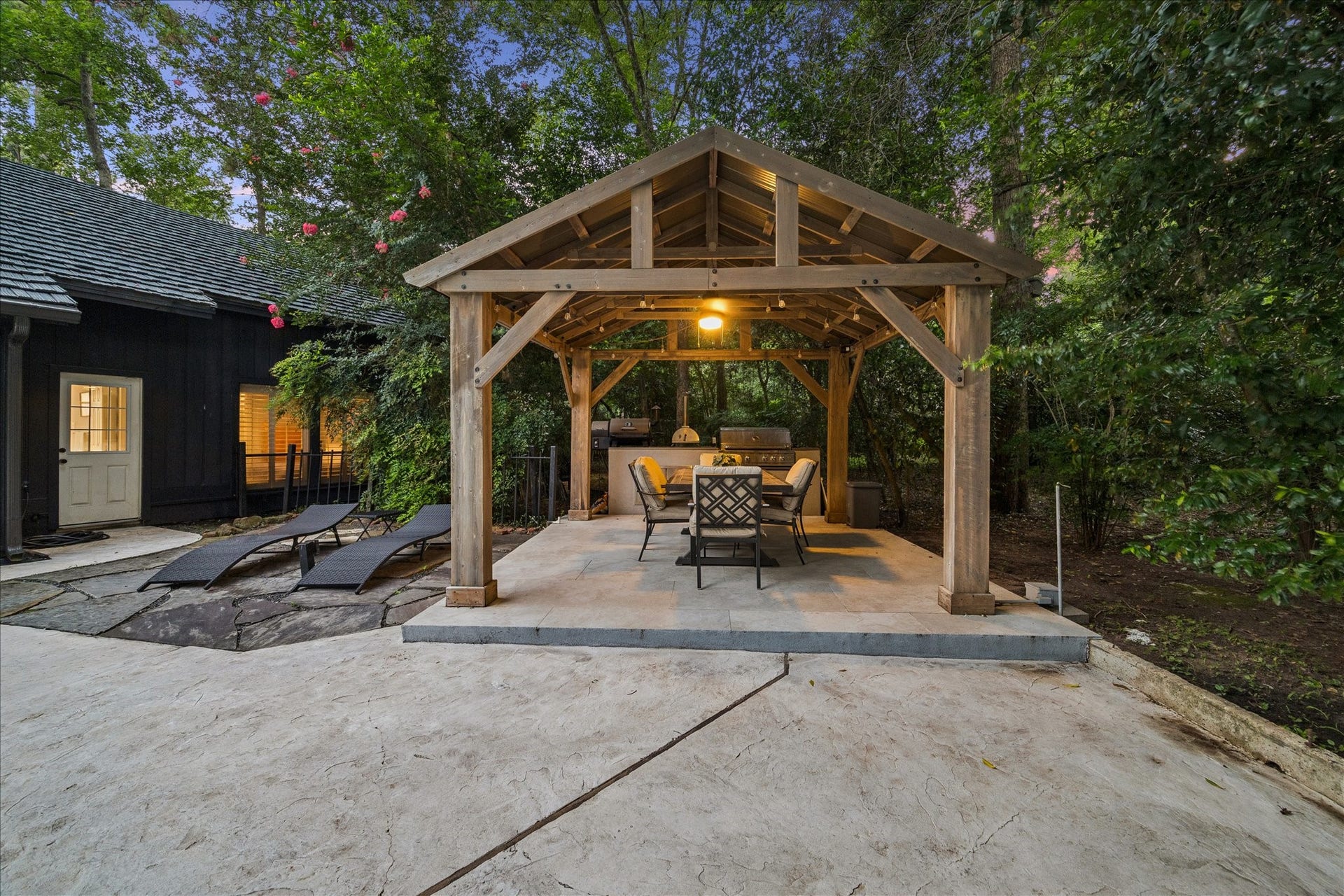 2411 Oakbank Drive, Kingwood, TX 77339 Enjoy lots of family gatherings in this serene backyard with a cozy wooden pergola, featuring outdoor seating and a dining area, ideal for entertaining.