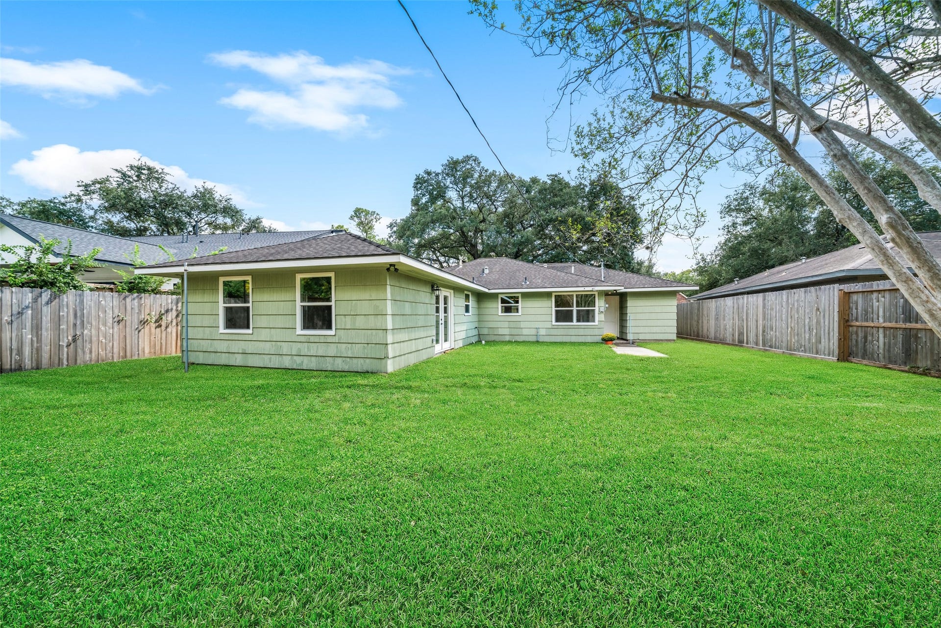 4806 Hummingbird Street, Houston, TX 77035 Spacious backyard with lush green lawn and privacy fencing, ideal for outdoor activities and relaxation.
