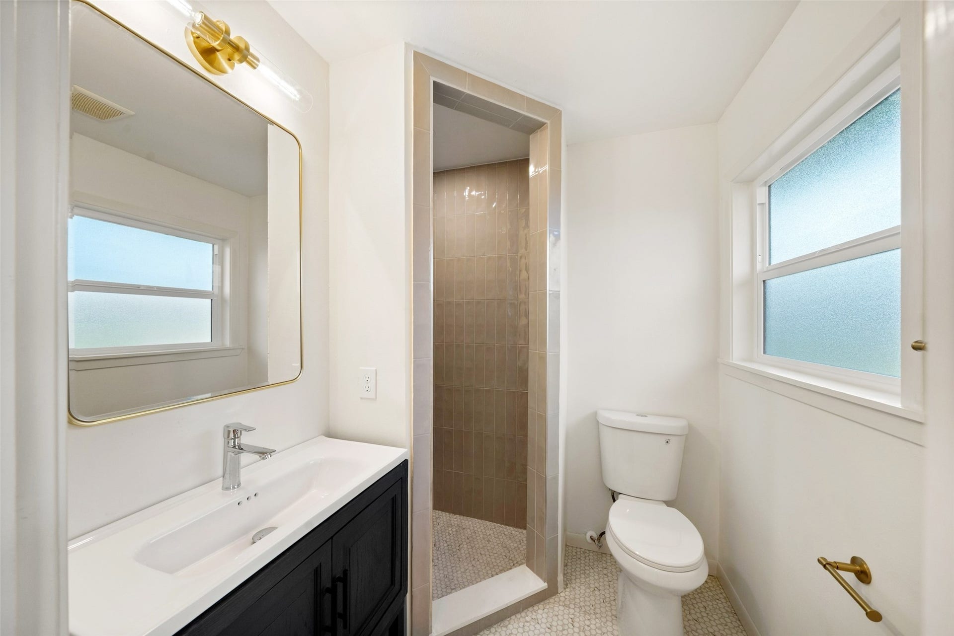 4806 Hummingbird Street, Houston, TX 77035 Bright and modern bathroom featuring a sleek walk-in shower, stylish vanity with a large mirror, and natural light from frosted windows.