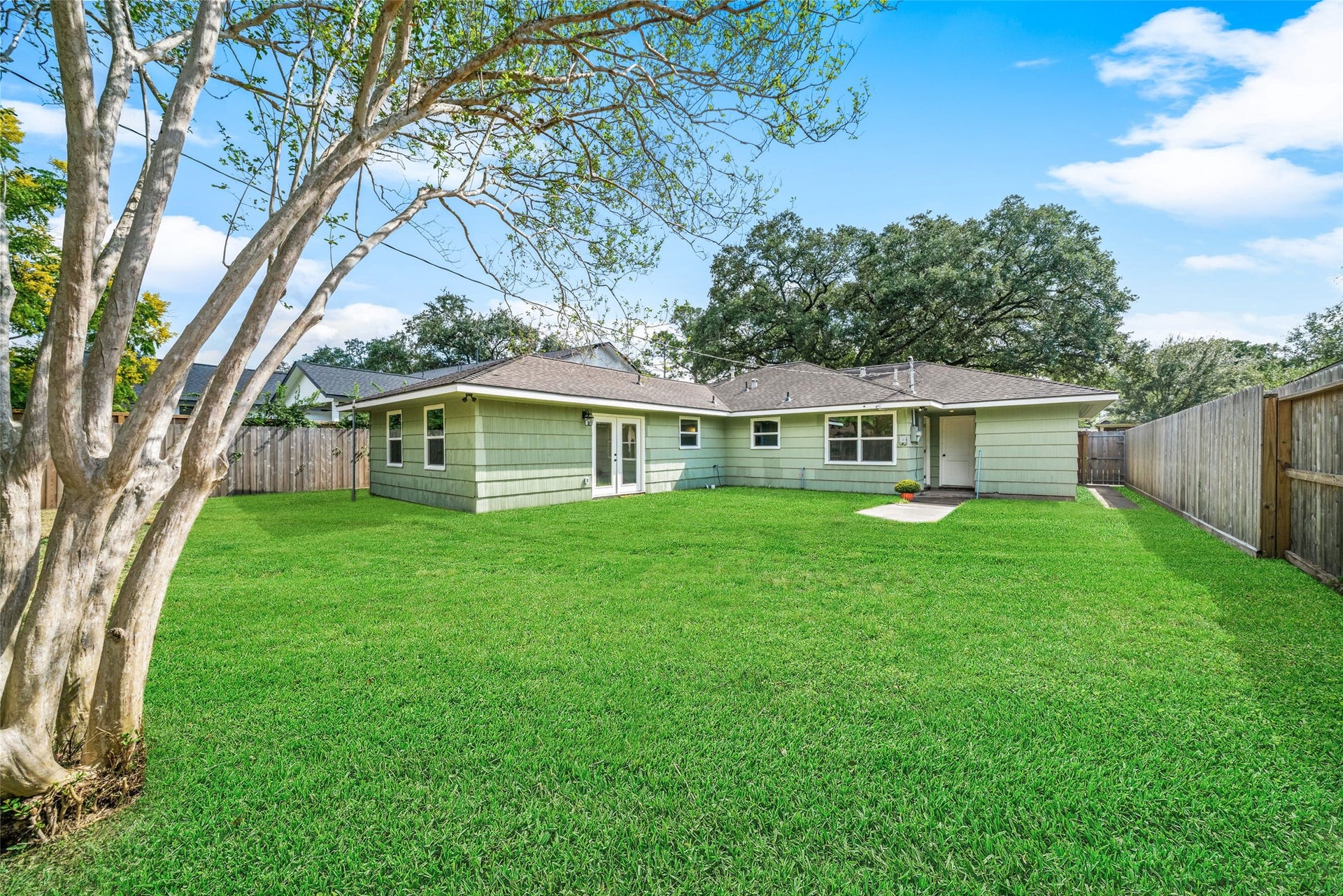 4806 Hummingbird Street, Houston, TX 77035 Spacious backyard with lush green lawn, mature trees, and a charming single-story home offering ample outdoor space for relaxation and entertaining.