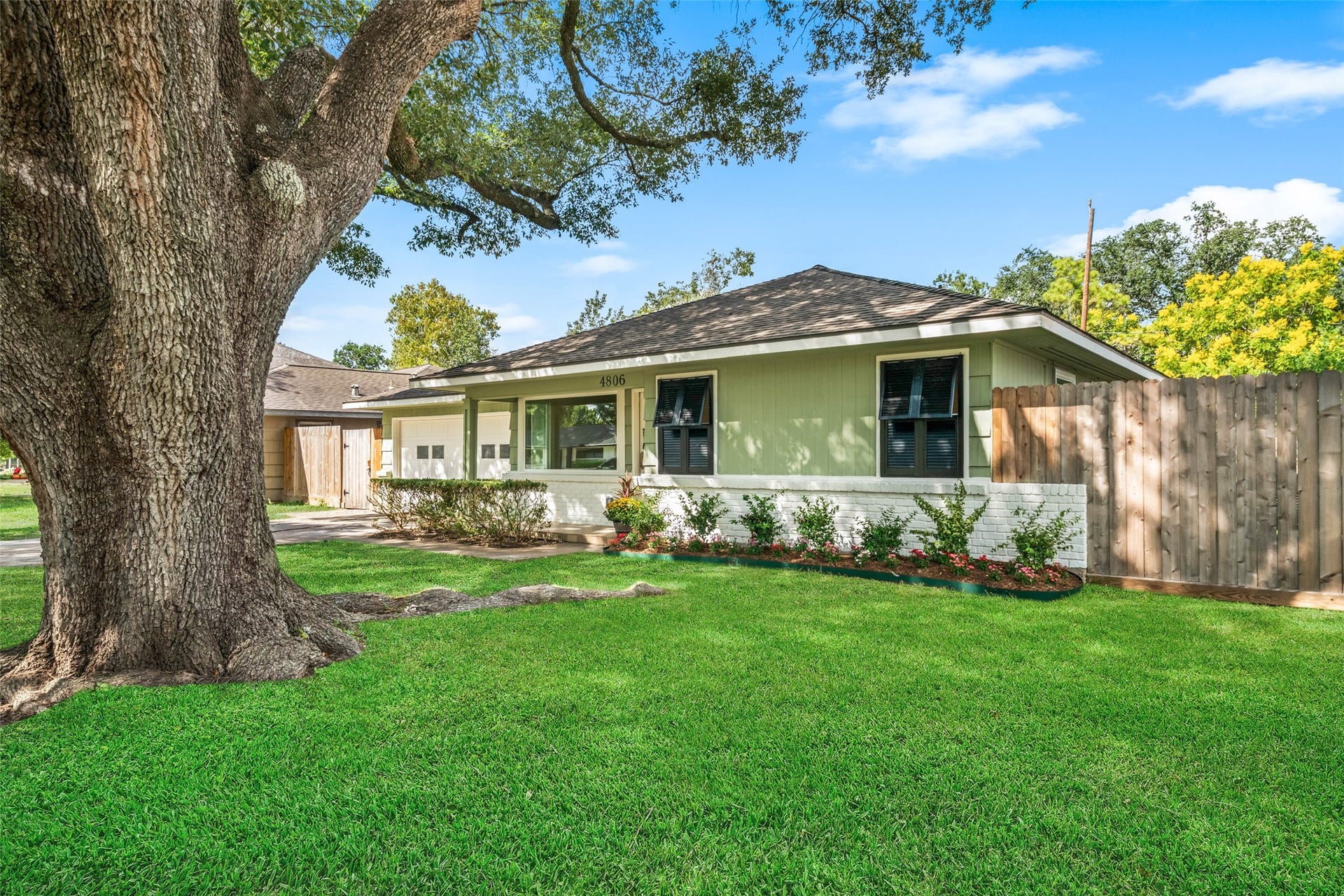 4806 Hummingbird Street, Houston, TX 77035 Charming home with lush green lawn and mature shade tree, complemented by a welcoming front porch and privacy fence.