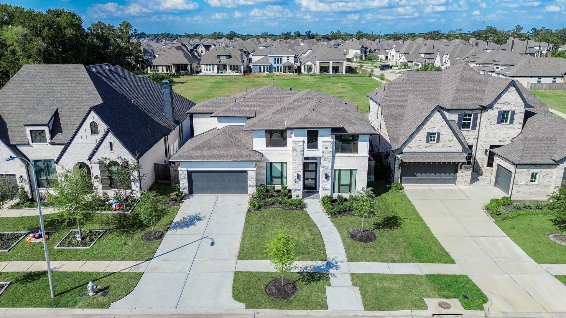Aerial view highlighting the home's striking architecture, attractive landscaping, and green space beyond.