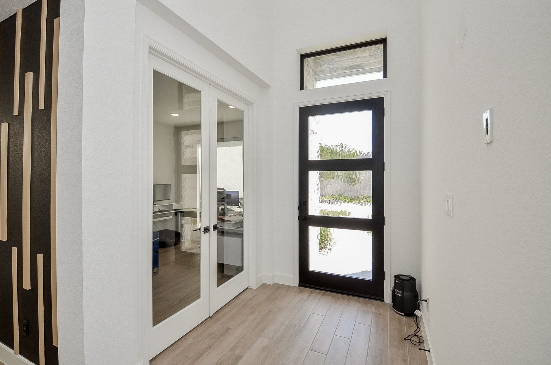 Bright, welcoming entry with stylish flooring and French doors leading to the private study.