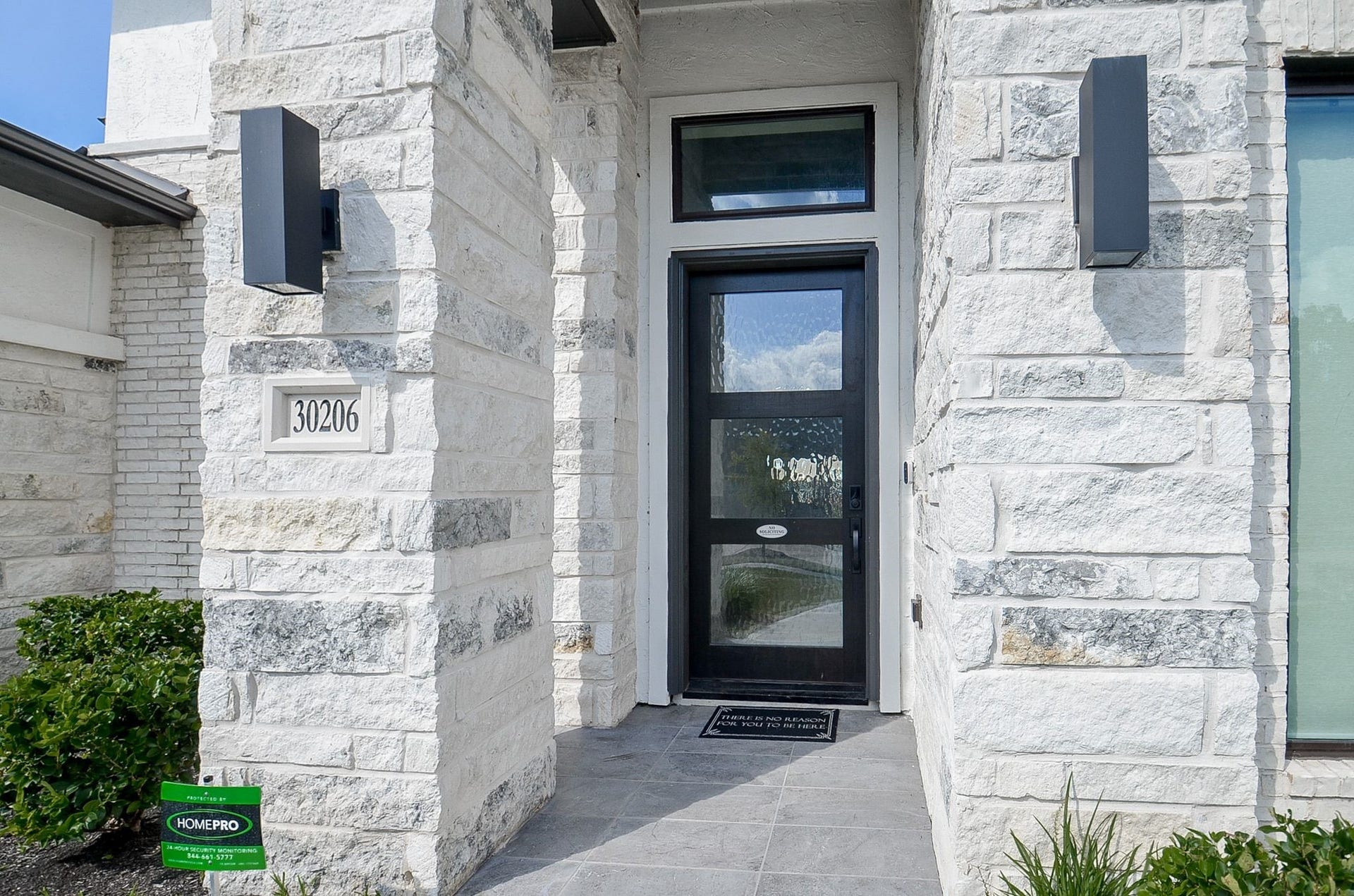 Entrance framed by gorgeous stone columns and a sleek glass door.