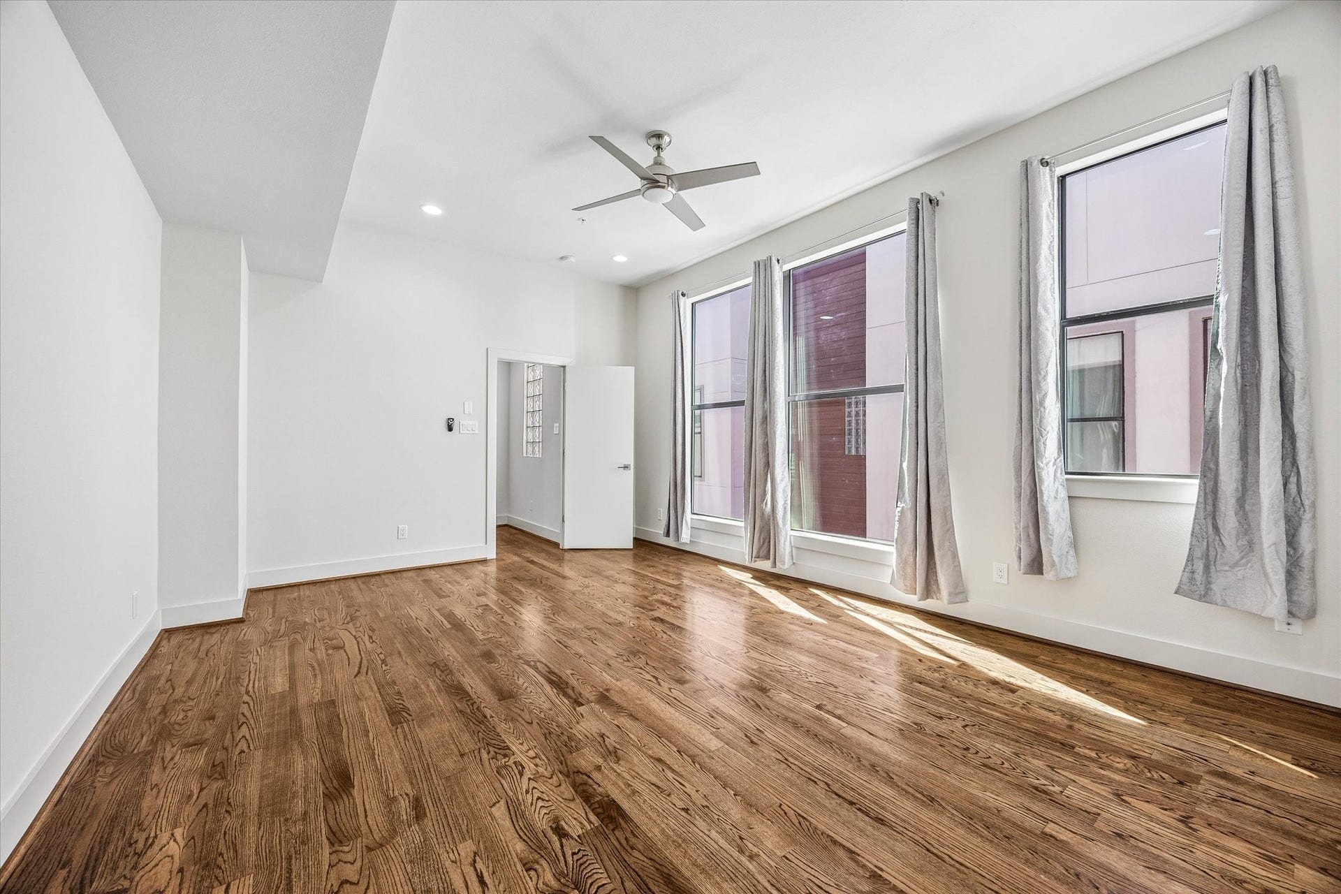 1215 Summer Street, #A, Houston, TX 77007 Light-filled primary bedroom with tall windows, high ceilings, wood flooring, recessed lighting, and a ceiling fan.
