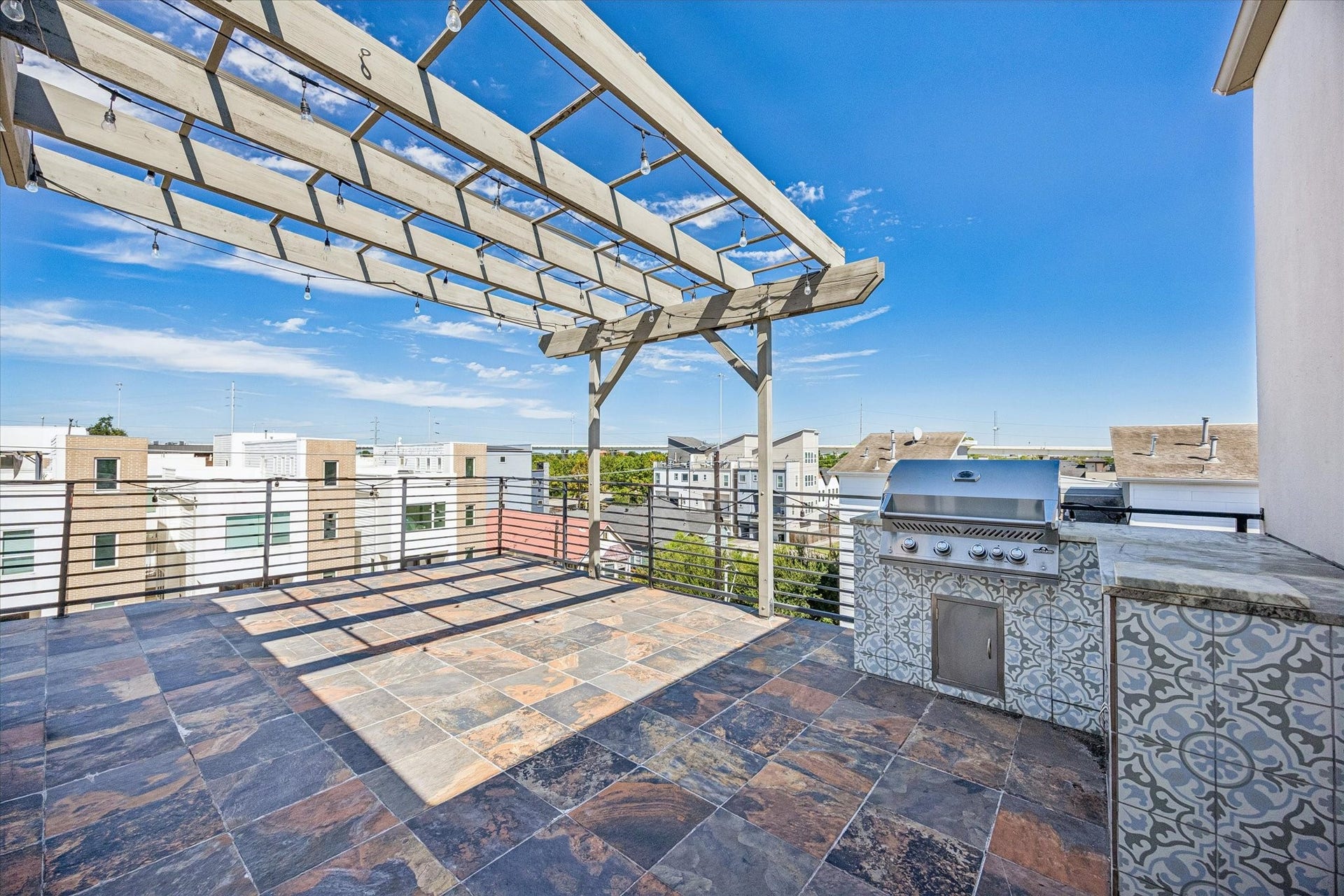 1215 Summer Street, #A, Houston, TX 77007 Spacious rooftop terrace featuring tile flooring, a pergola, horizontal metal railings, and a built-in grilling station with adjacent counter space.