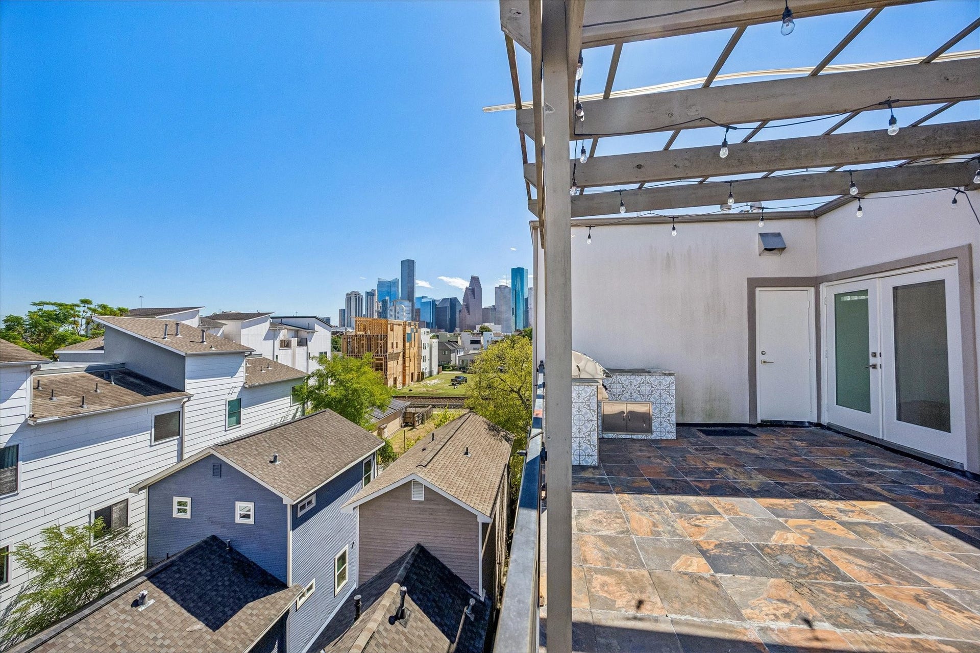 1215 Summer Street, #A, Houston, TX 77007 City skyline views create a striking backdrop for the rooftop terrace, featuring tile flooring, a pergola, and direct access to the upper-level interior.