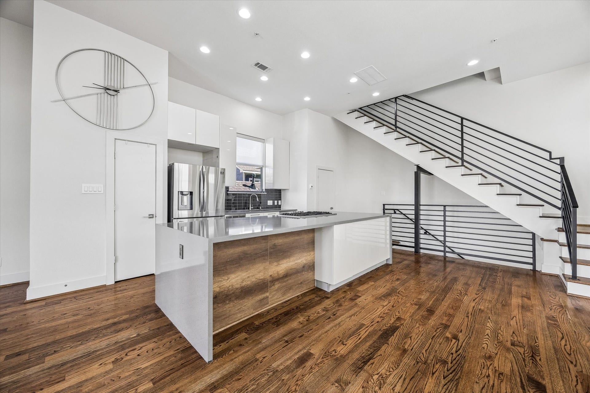 1215 Summer Street, #A, Houston, TX 77007 Expansive kitchen island features waterfall edges, integrated cabinetry, and generous counter space. White cabinets and stainless steel appliances complement the kitchens contemporary design.