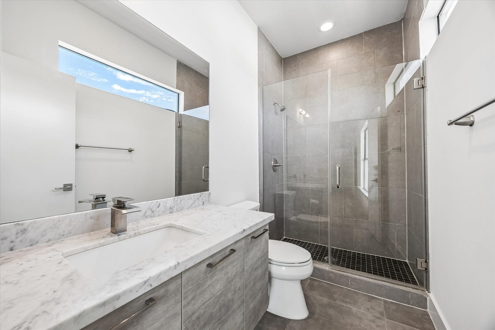 1215 Summer Street, #A, Houston, TX 77007 Full bathroom featuring a glass-enclosed walk-in shower, full-height tile, and a clerestory window. A spacious vanity provides counter space and storage.