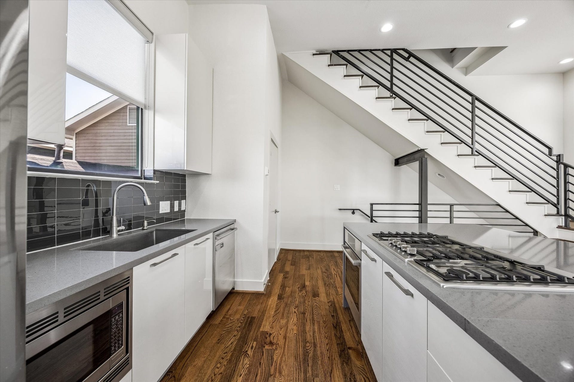 1215 Summer Street, #A, Houston, TX 77007 Kitchen features a gas cooktop, built-in oven and microwave, dishwasher, and undermount sink beneath a window. Generous cabinetry and counter space provide practical storage and preparation areas.