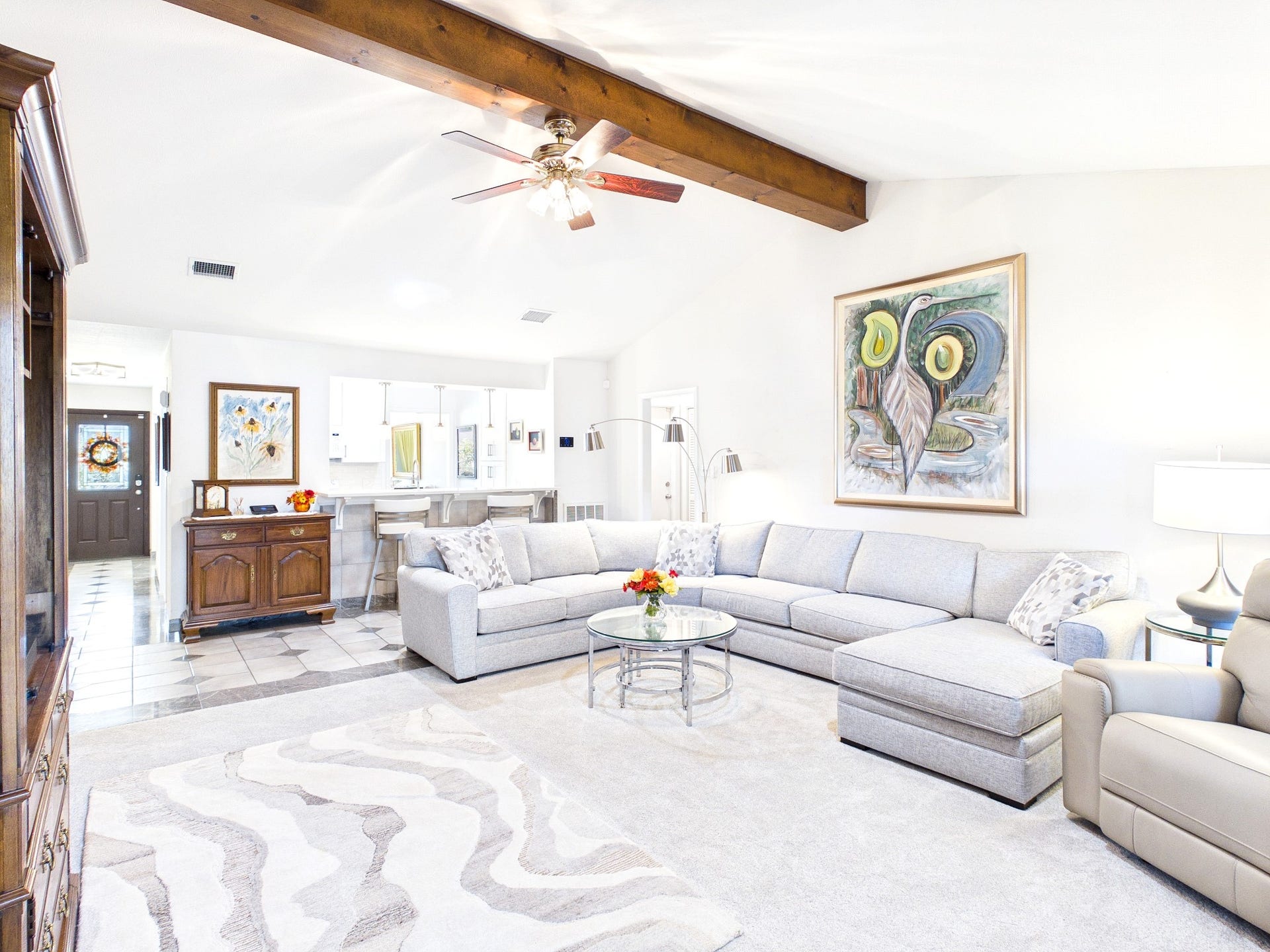 Expansive living area with abundant natural light, featuring a comfortable sectional sofa, elegant decor, and a seamless flow to the kitchen, perfect for relaxation and entertaining.