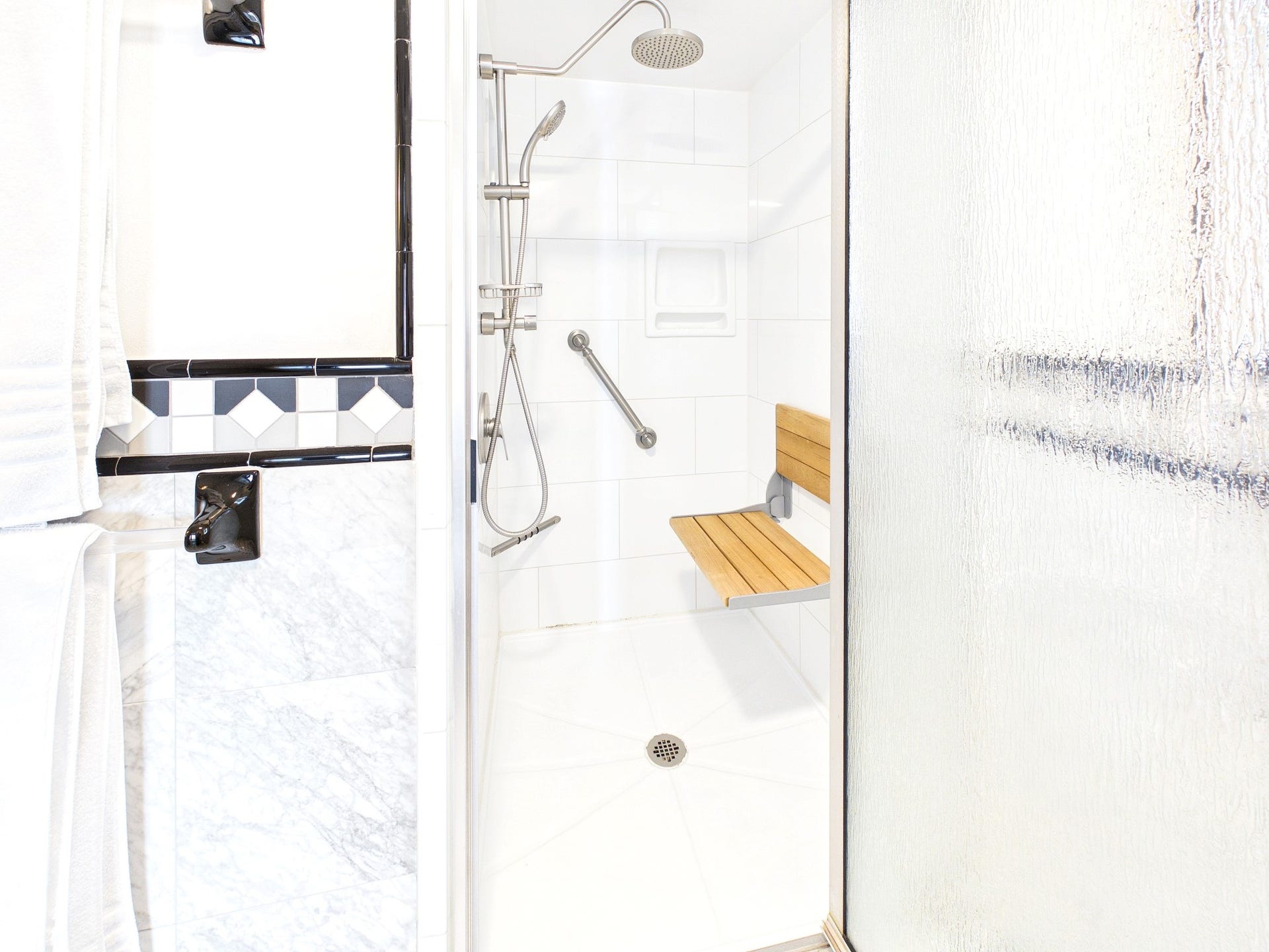 Experience ultimate relaxation in this luxurious bath, featuring sleek fixtures, elegant tilework, and a chic walk-in shower with a convenient fold-down seat.