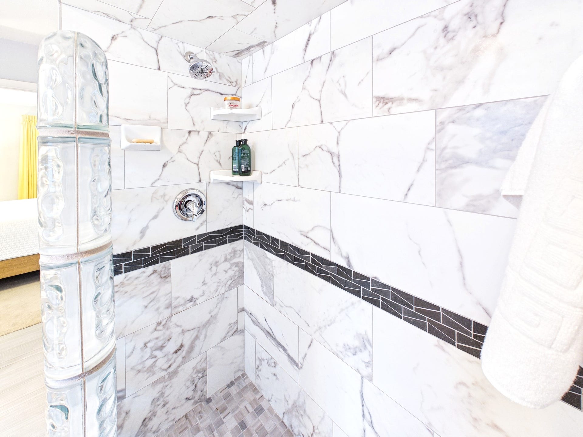 Indulge in the luxurious elegance of a primary shower adorned with sleek marble tiles and stylish accents, offering a serene escape.
