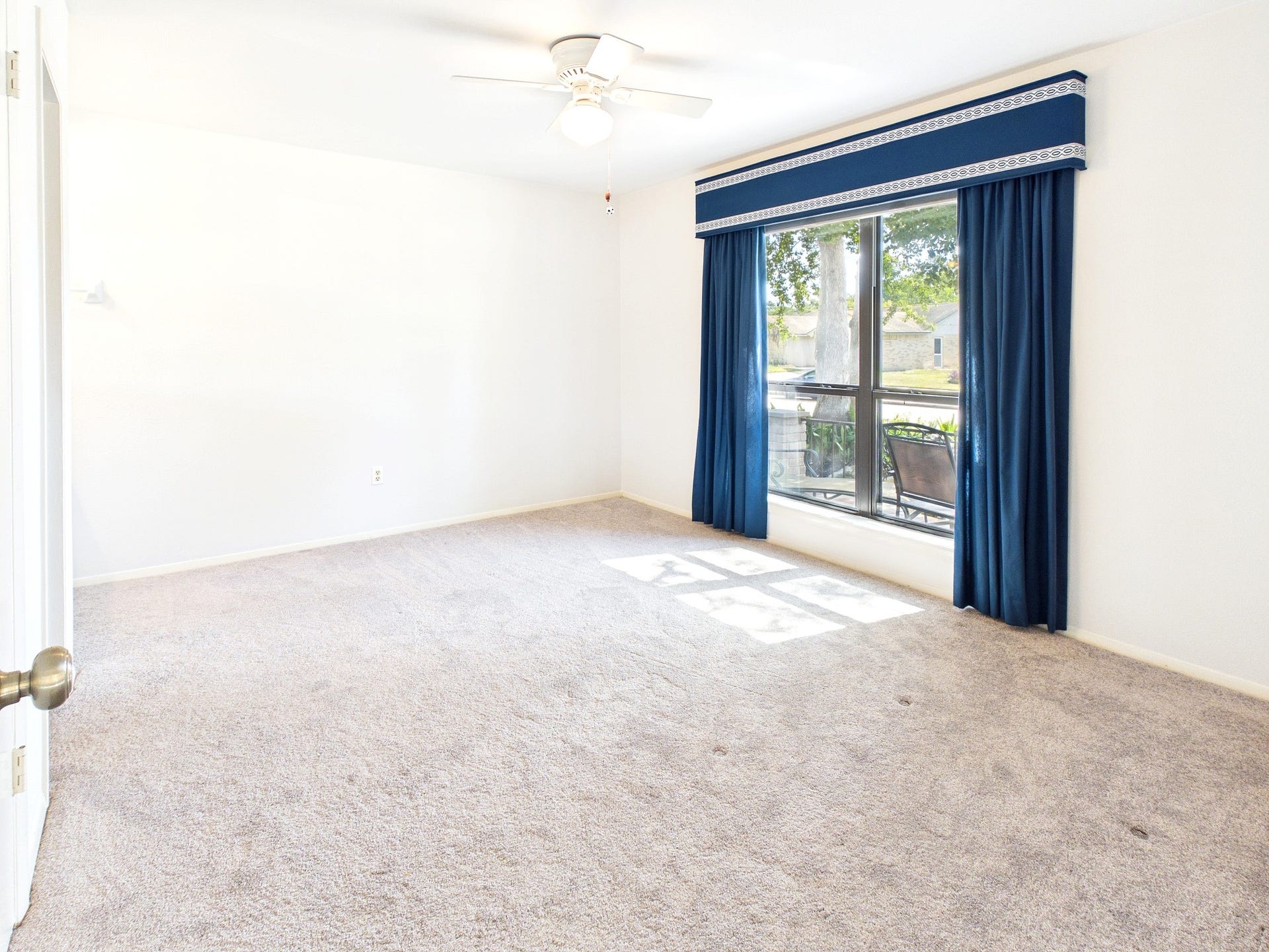 Expansive guest room filled with natural light, featuring plush carpeting and elegant blue drapery, perfect for relaxation and comfort.