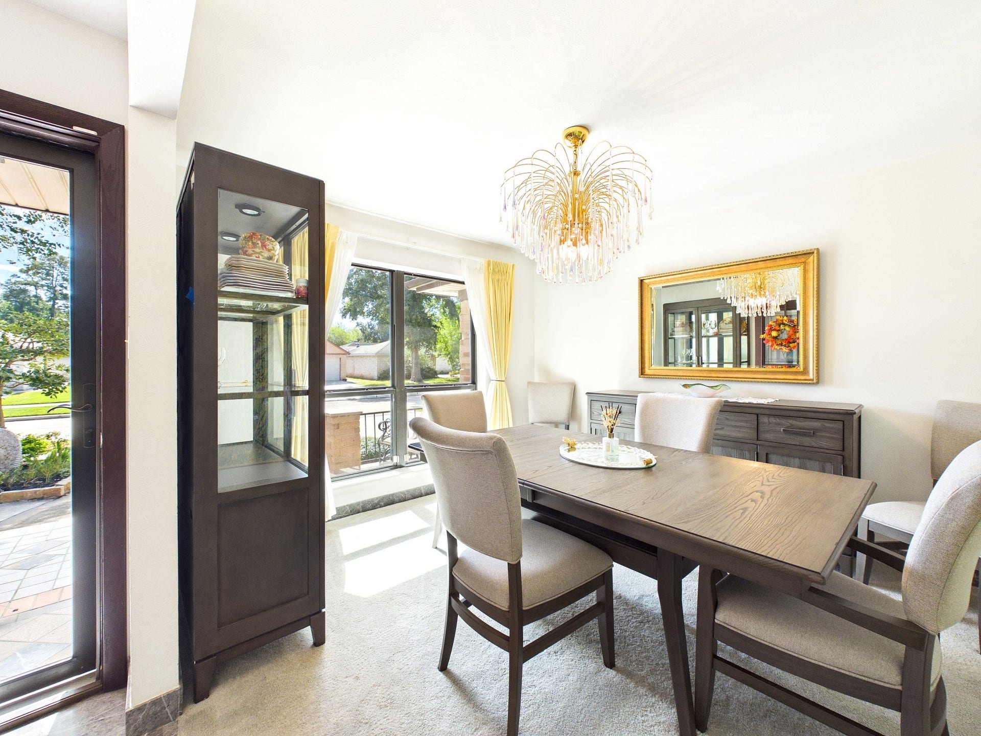 Elegant formal dining room bathed in natural light, featuring a striking chandelier and sophisticated furnishings, perfect for hosting memorable gatherings.