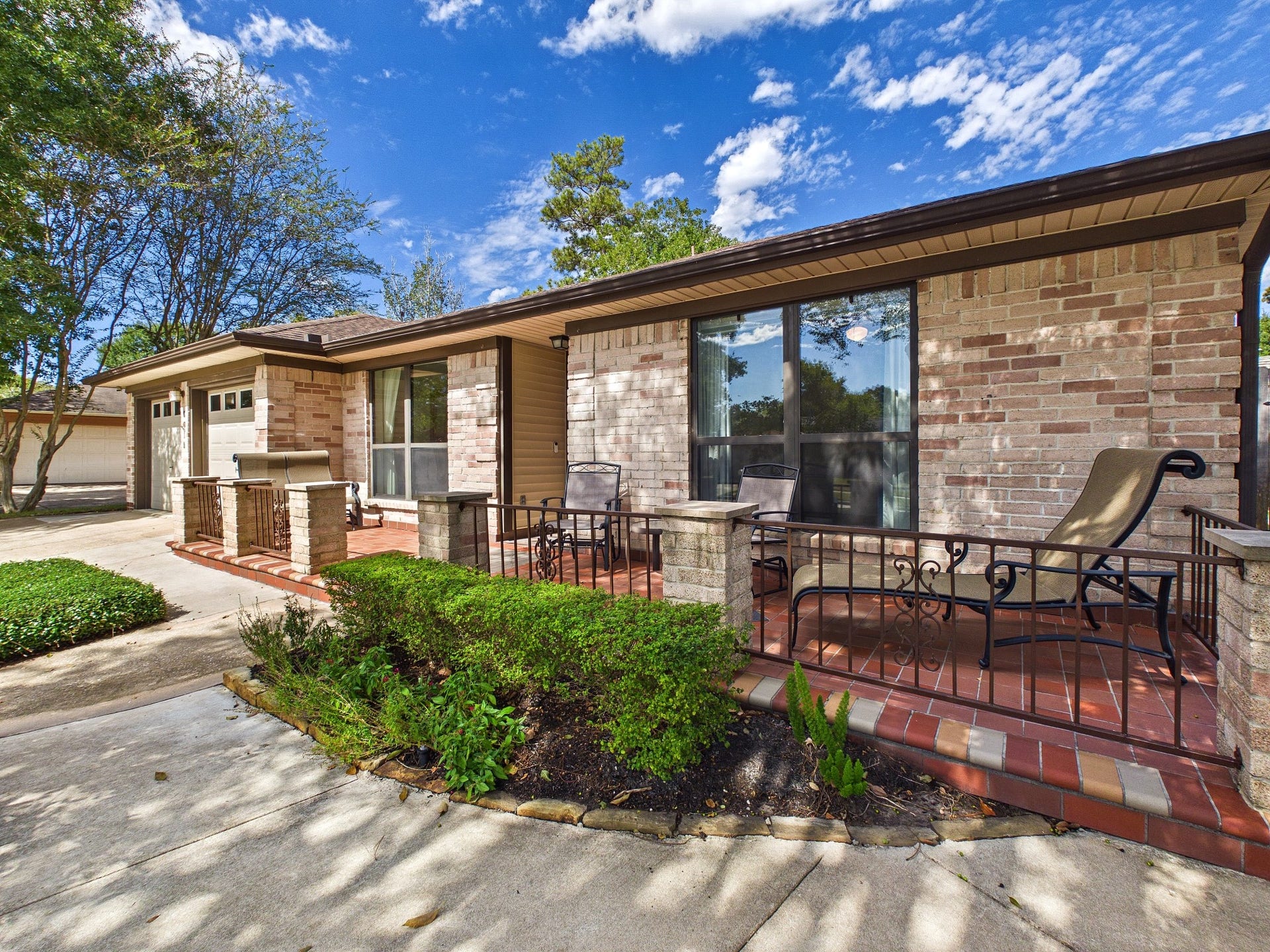 Charming ranch-style home with a welcoming front porch, perfect for relaxing. The brick exterior and large windows enhance its curb appeal, set against a beautifully landscaped yard.