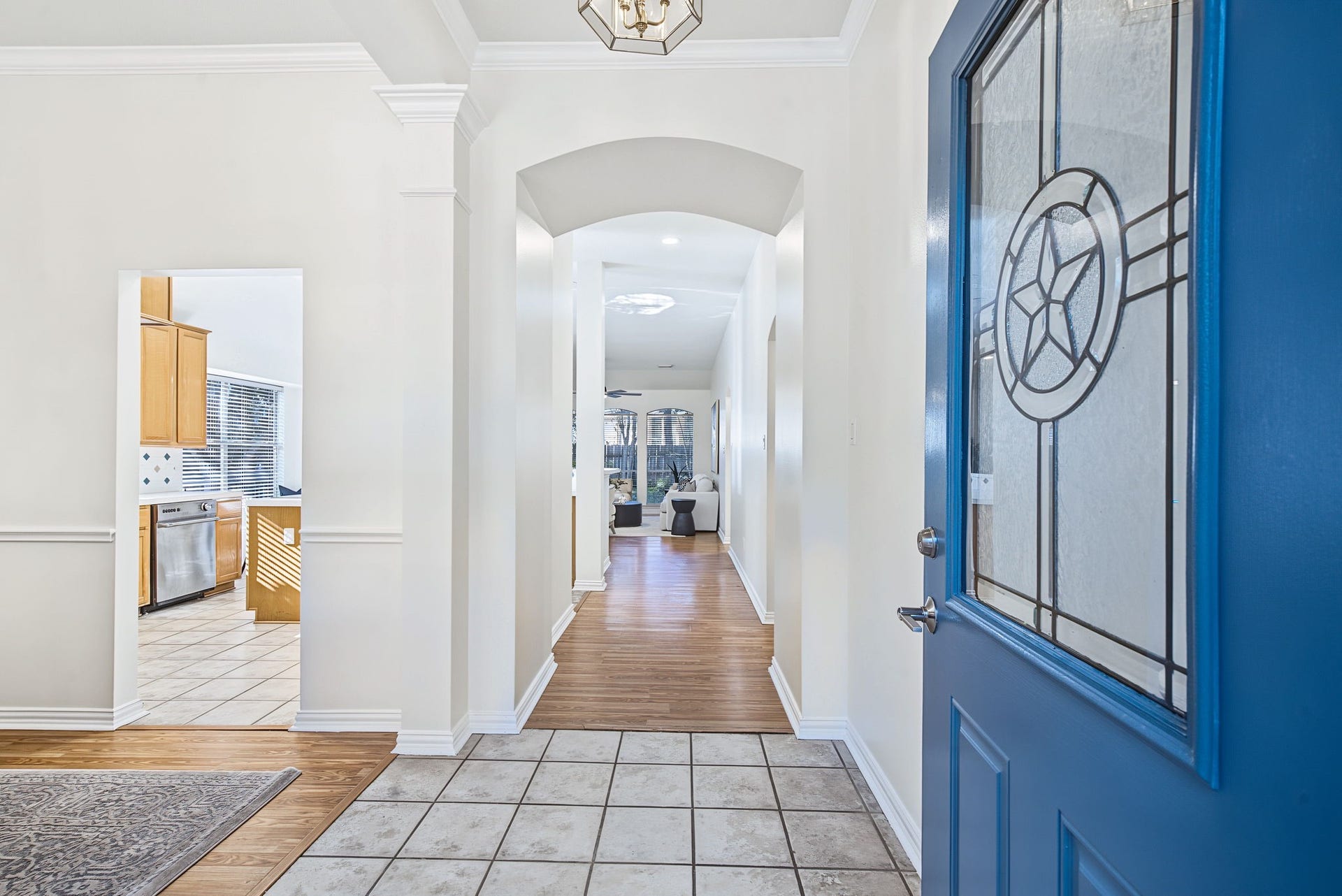 51 Pinery Ridge Place, The Woodlands, TX 77382 A decorative glass front door opens to a bright entry with arched architectural details, fresh neutral paint, and a welcoming view into the home.