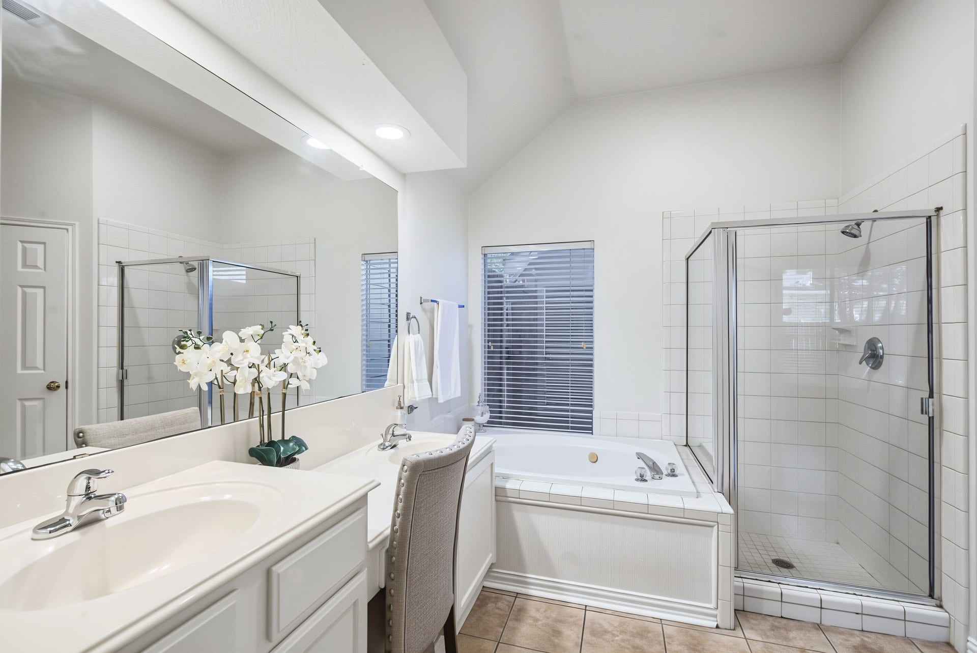 51 Pinery Ridge Place, The Woodlands, TX 77382 Dual sinks, a seated vanity area, a soaking tub, and a separate glass-enclosed shower give the primary bathroom a practical, spacious layout.