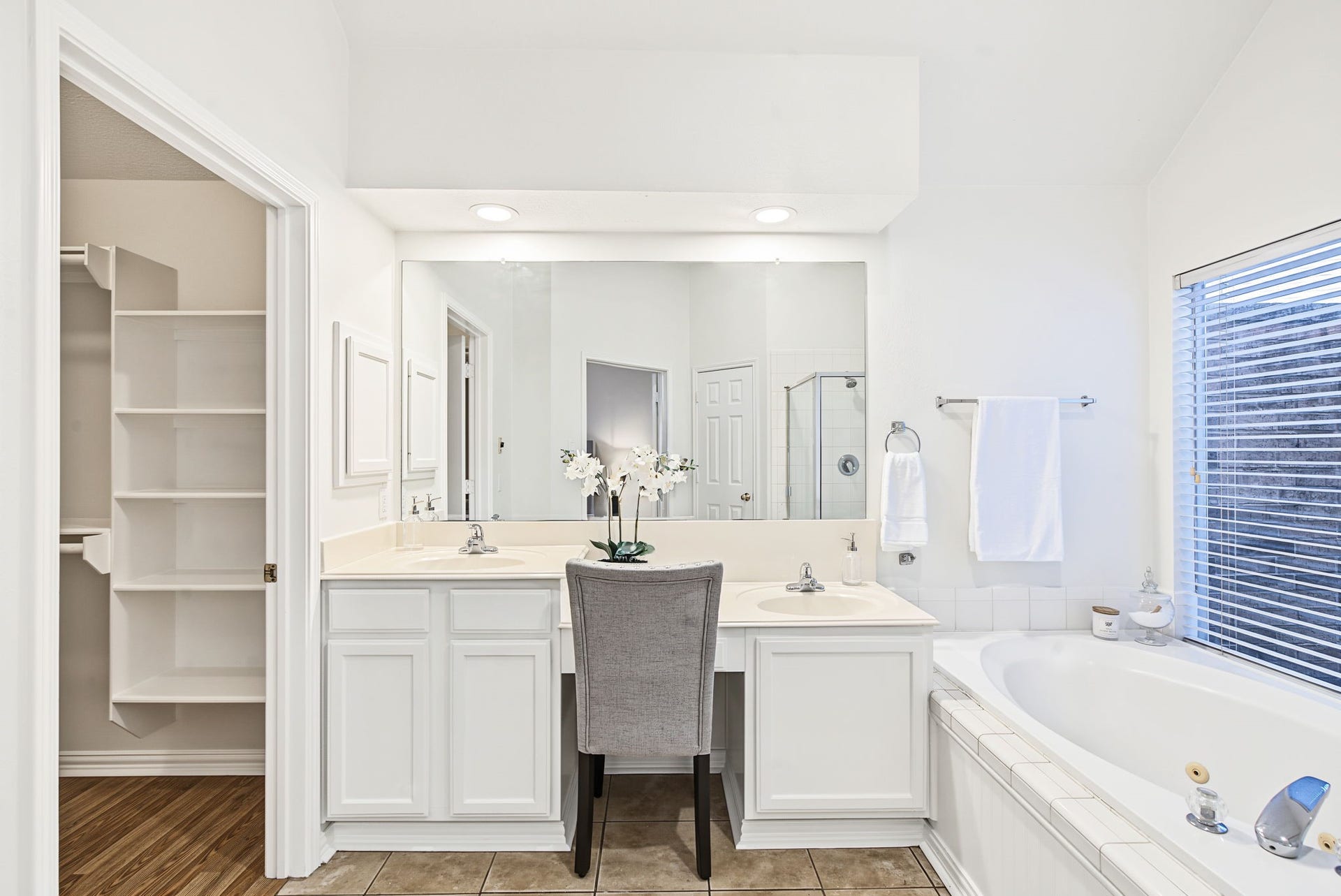 51 Pinery Ridge Place, The Woodlands, TX 77382 Built-in linen shelving, vanity storage, and a seated dressing area help keep the primary bathroom organized.