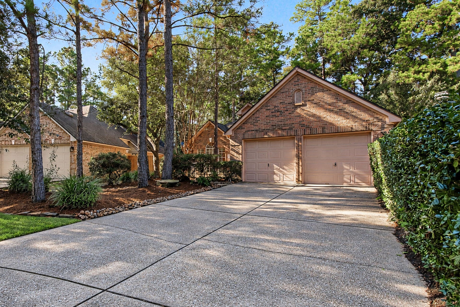51 Pinery Ridge Place, The Woodlands, TX 77382 A broad double-wide driveway leads to the attached two-car garage, with mature landscaping adding character to the approach.