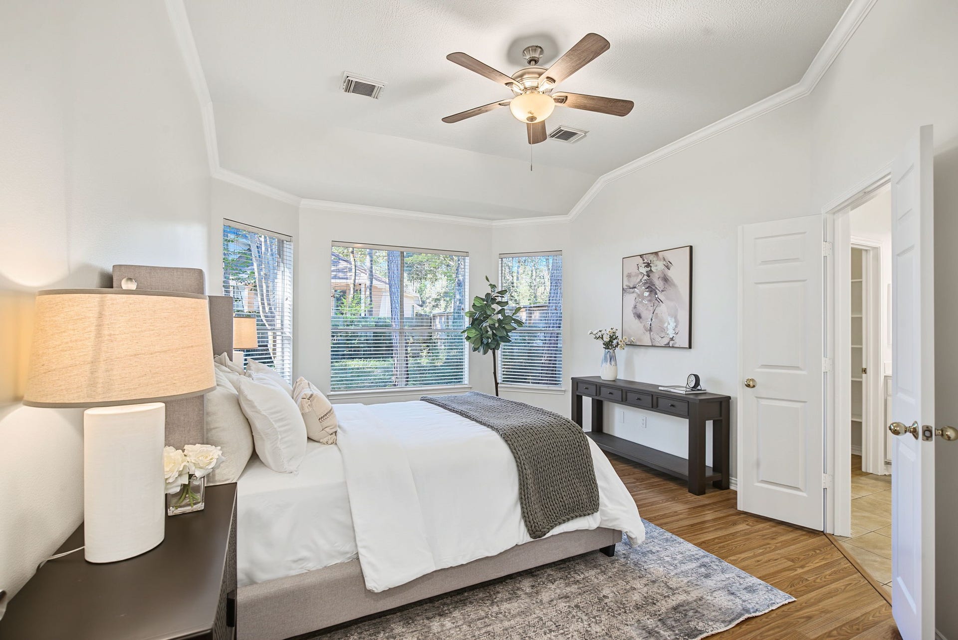 51 Pinery Ridge Place, The Woodlands, TX 77382 The primary suite offers a retreat with a raised ceiling, crown molding, and a window-lined wall overlooking the backyard.
