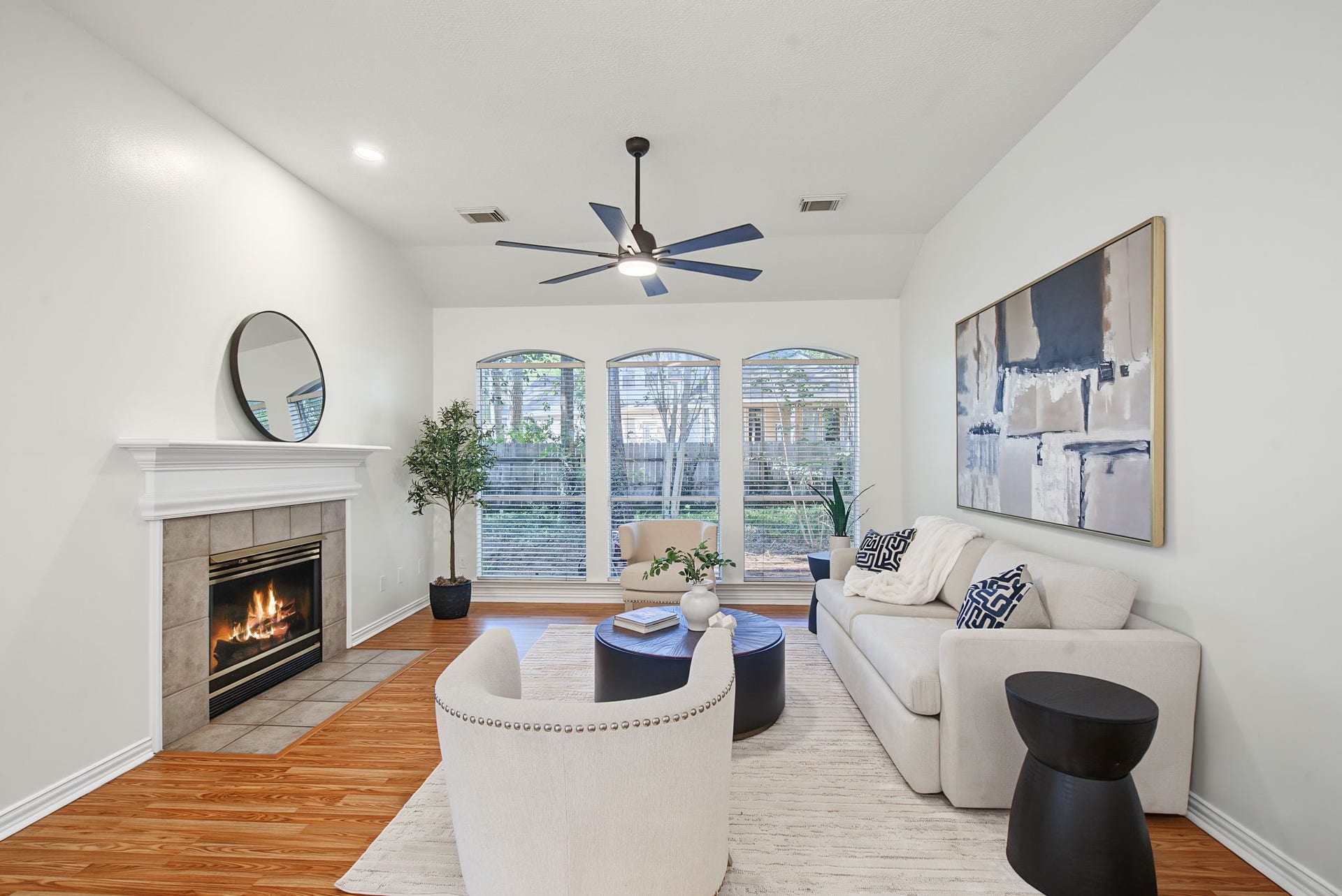 51 Pinery Ridge Place, The Woodlands, TX 77382 Gather around the fireplace in a living room filled with natural light, backyard views, and warm wood-look flooring.