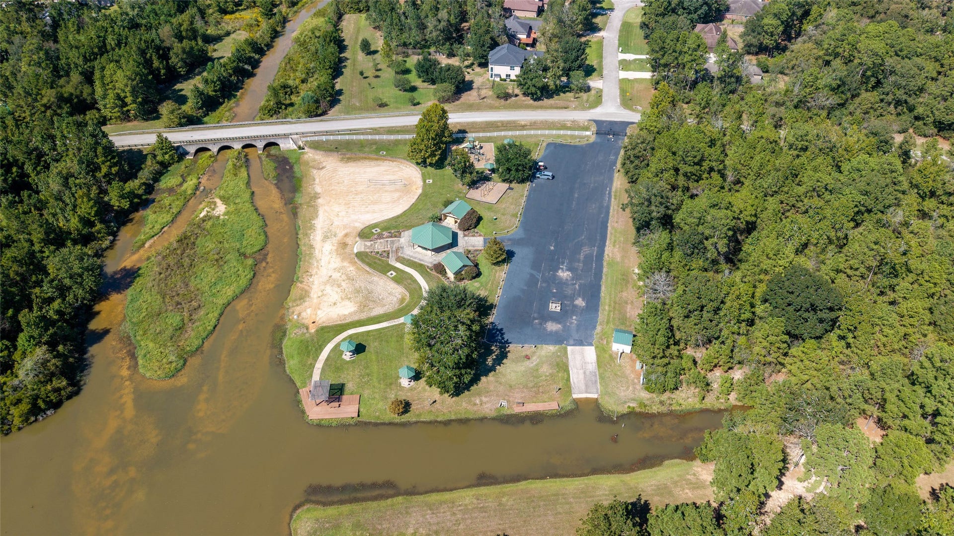 0 Ridgelake Court, Montgomery, TX 77316 Scenic lakeside property featuring lush greenery, a spacious parking area, and charming picnic spots, perfect for outdoor enthusiasts and relaxation.