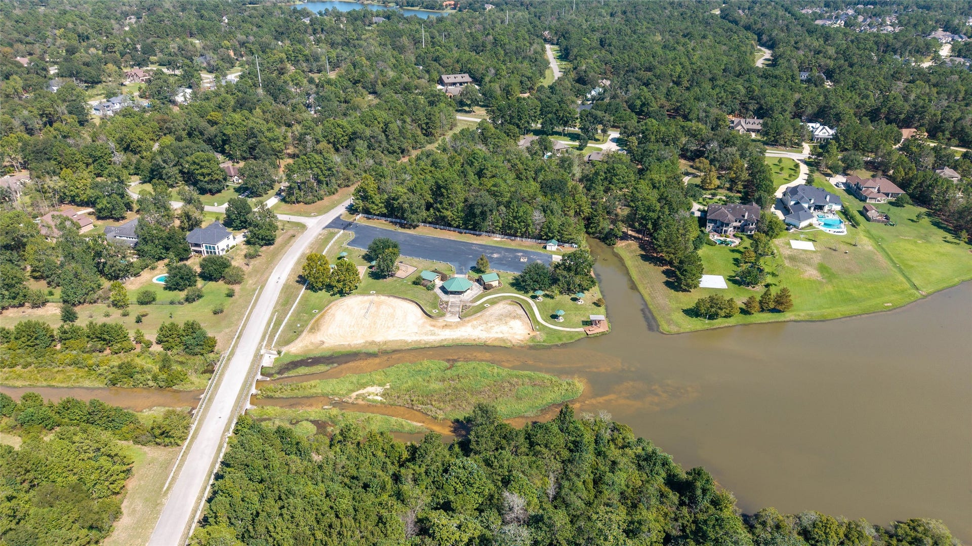 0 Ridgelake Court, Montgomery, TX 77316 Expansive wooded landscape with a serene lake, surrounded by spacious homes and lush greenery, offering a tranquil and private setting.