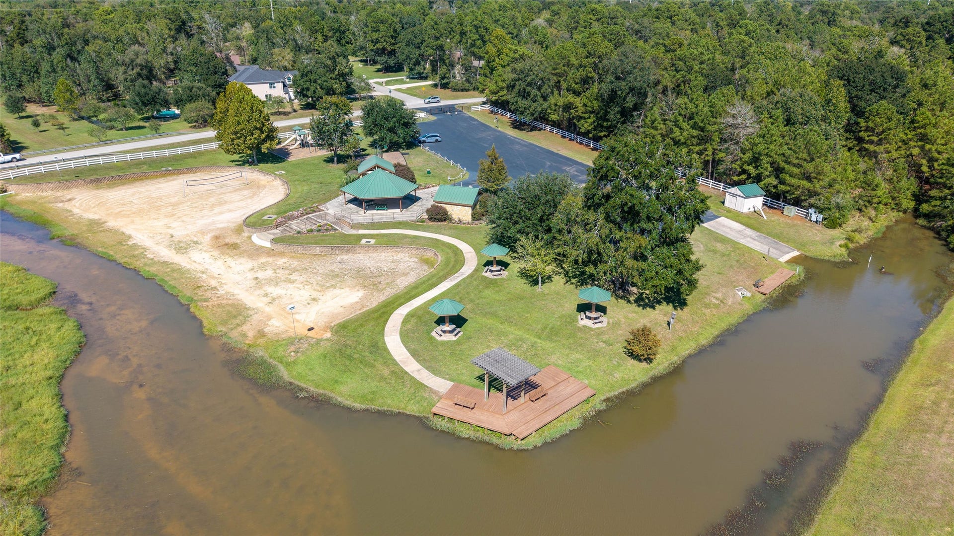 0 Ridgelake Court, Montgomery, TX 77316 Discover a picturesque lakeside retreat featuring a large covered pavillion, covered picnic tabes, a winding path, and lush greenery, perfect for relaxation and outdoor activities.