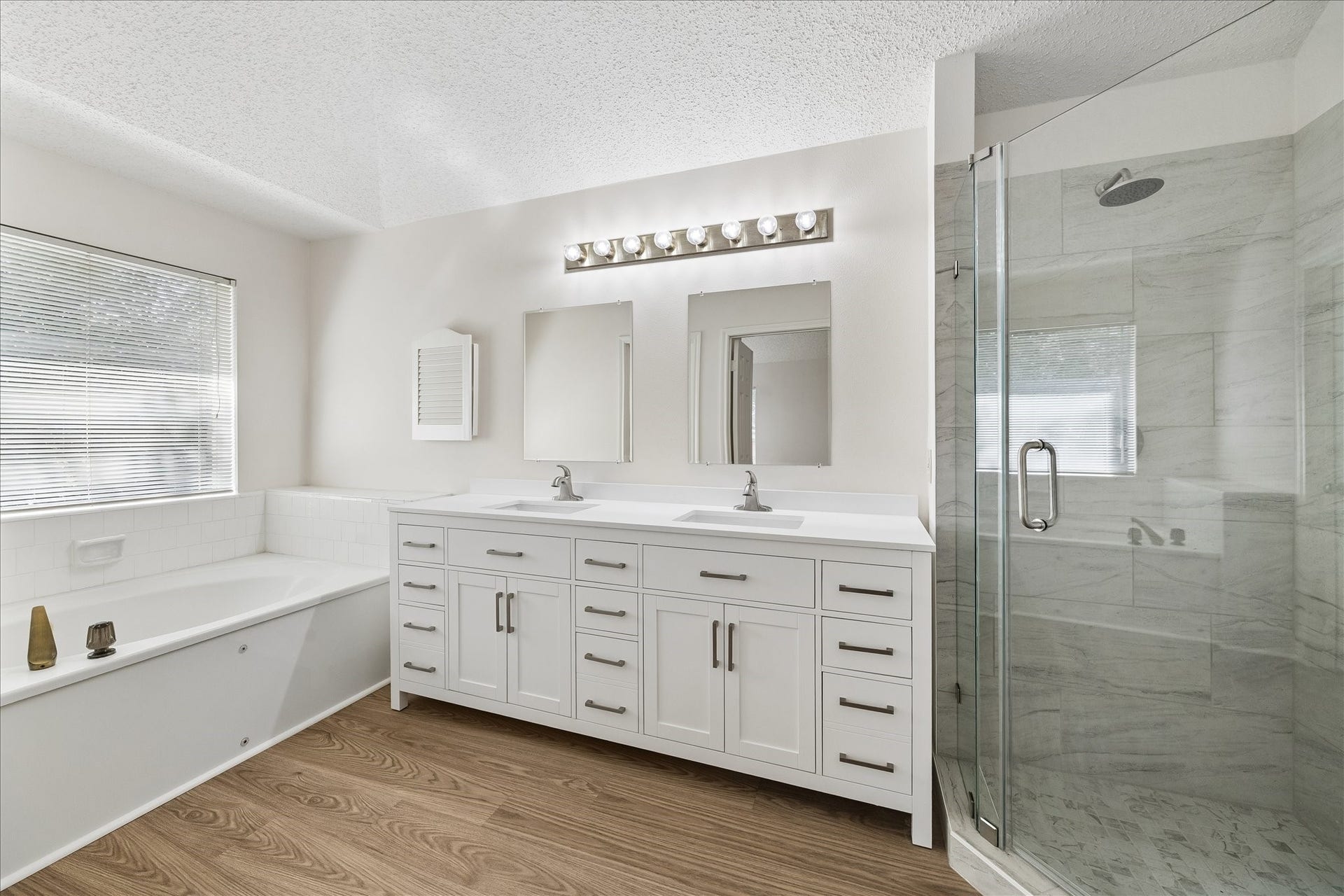 15503 Ensenada Drive, Houston, TX 77083 Tastefully remodeled primary bathroom with new flooring, cabinets, double sinks, mirrors and glass enclosed shower.