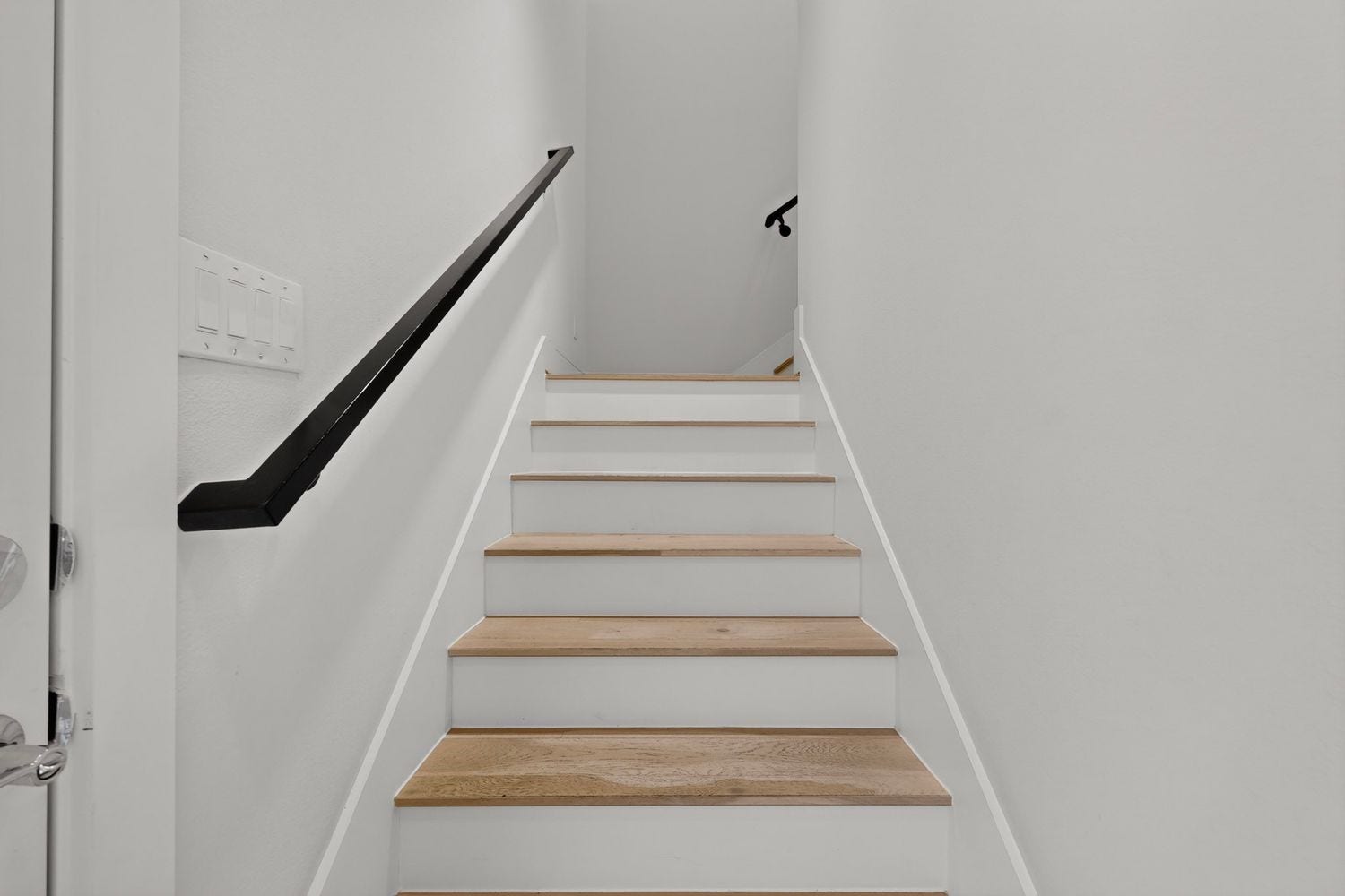 9820 Mocking Bird Hill Lane, Houston, TX 77080 Stylish staircase featuring light wood steps and sleek black handrails, exuding modern elegance.