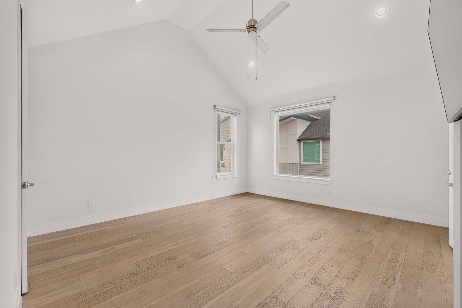 9820 Mocking Bird Hill Lane, Houston, TX 77080 A vacant view of the bright and airy bedroom featuring vaulted ceilings, large windows for natural light, and sleek wood flooring, creating a serene and inviting space.